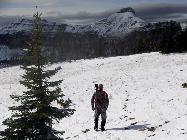 A man is standing on top of a snow covered hill.