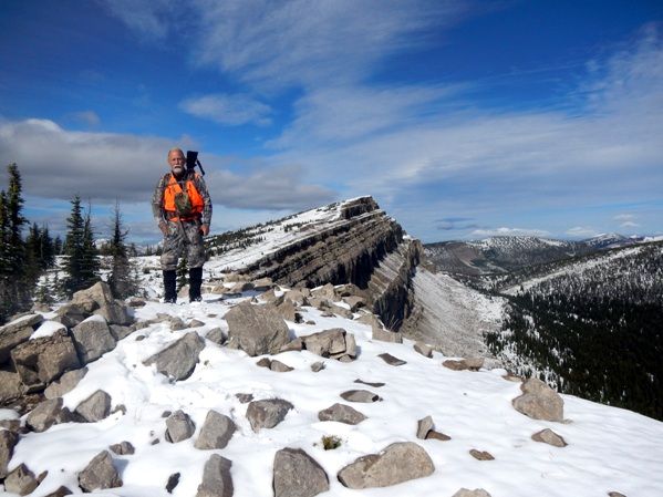 A man is standing on top of a snow covered mountain.