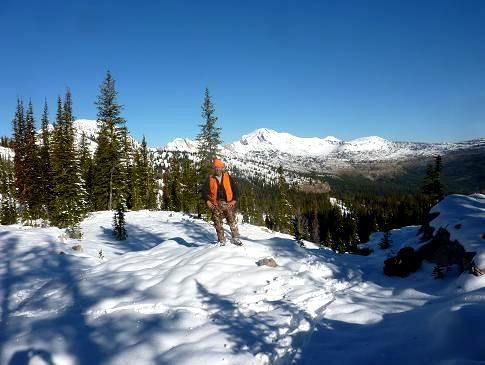 A man is standing in the snow on top of a snow covered mountain.