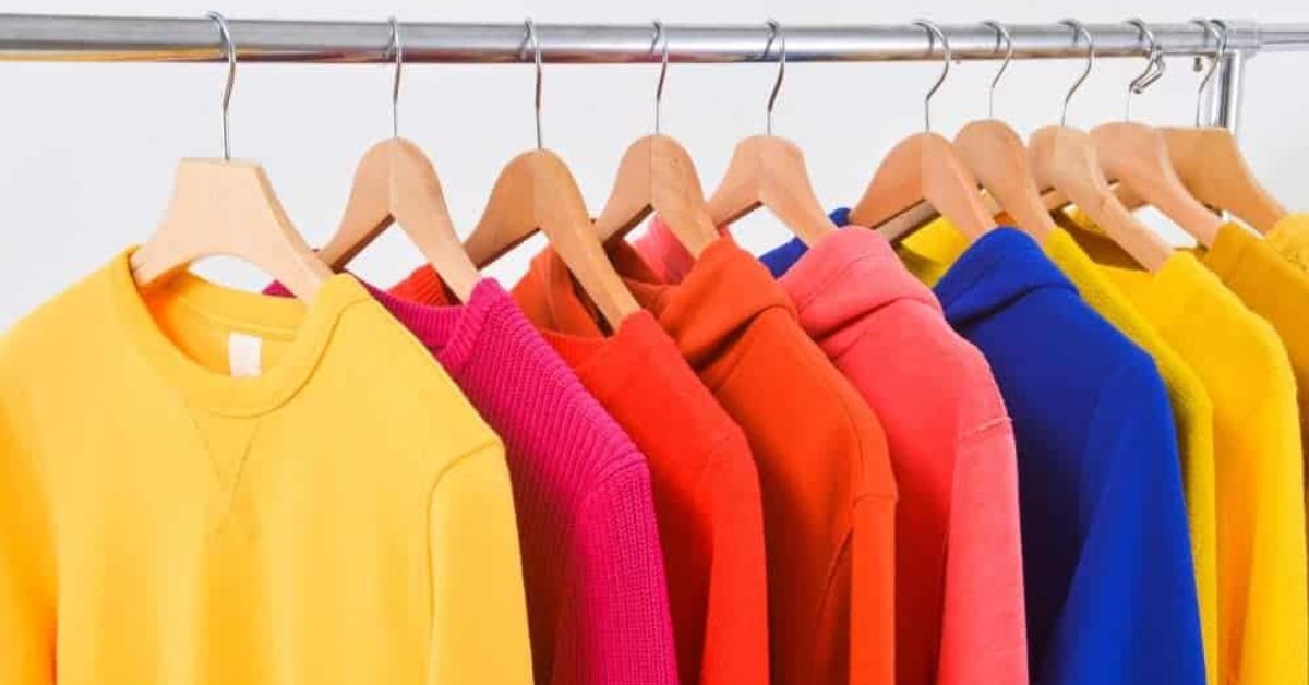 A row of colorful sweaters hanging on a rack.