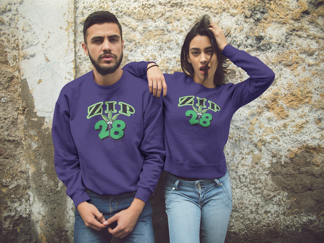 A man and a woman wearing purple sweatshirts with the number 28 on them