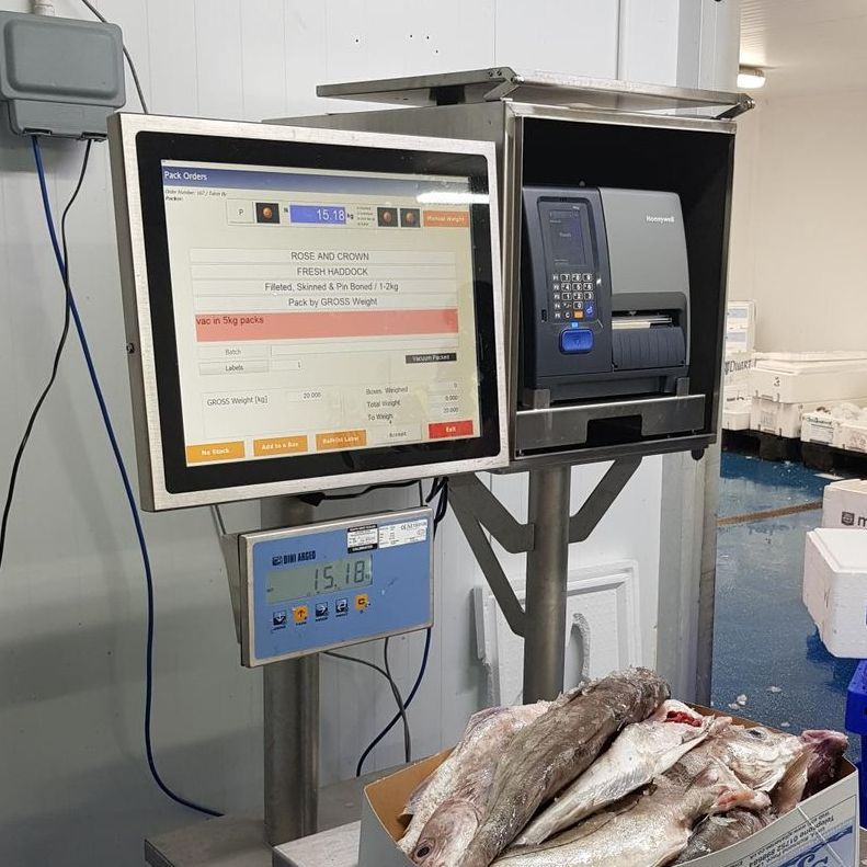 A OCM computer monitor is sitting on top of a scale next to a box of fish.