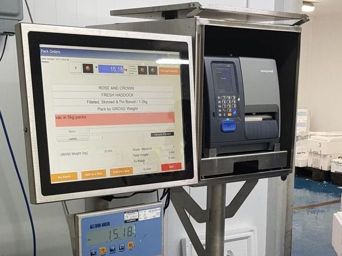 An OCM computer monitor is sitting on top of a scale in a fish processing factory.