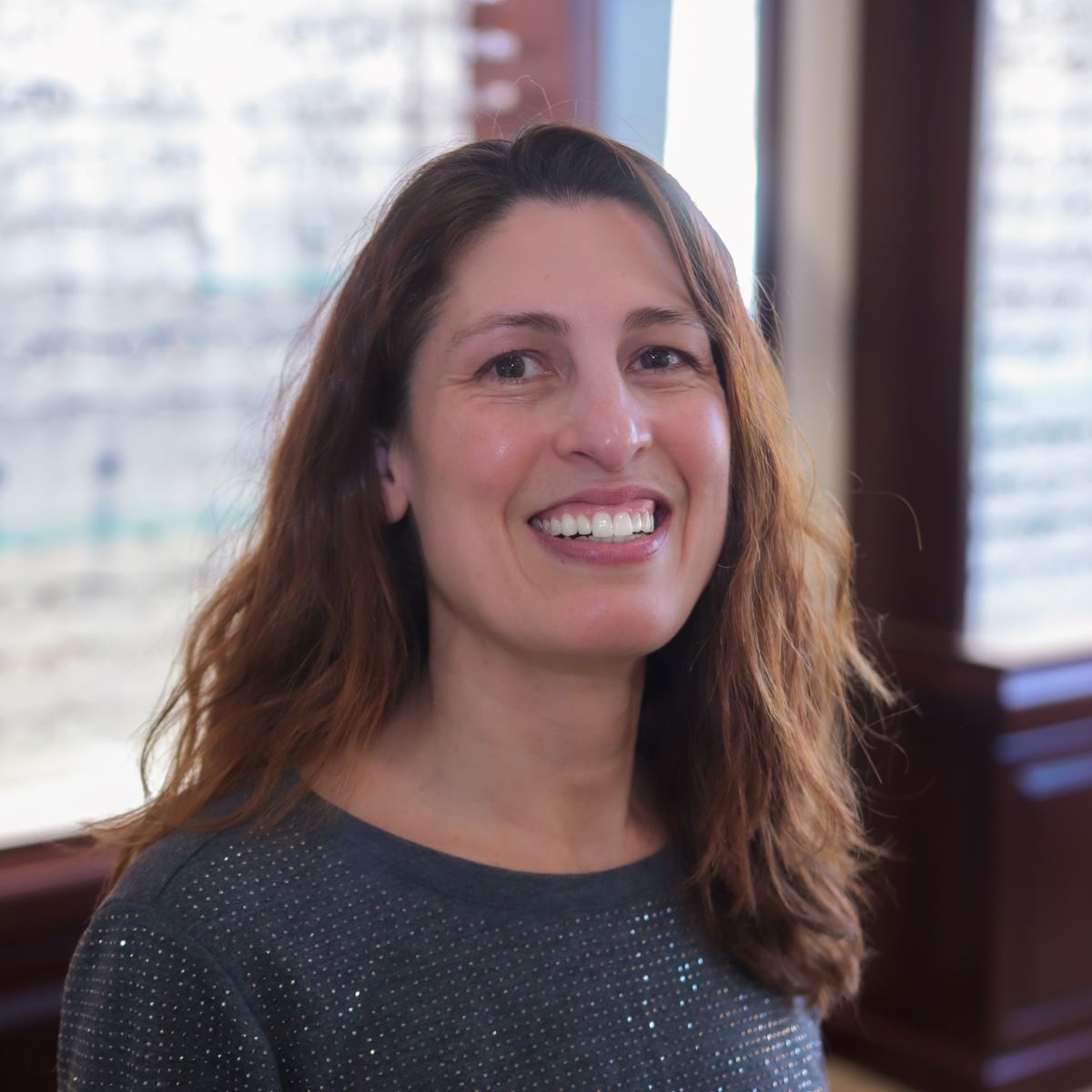 A woman wearing a grey sweater is smiling for the camera