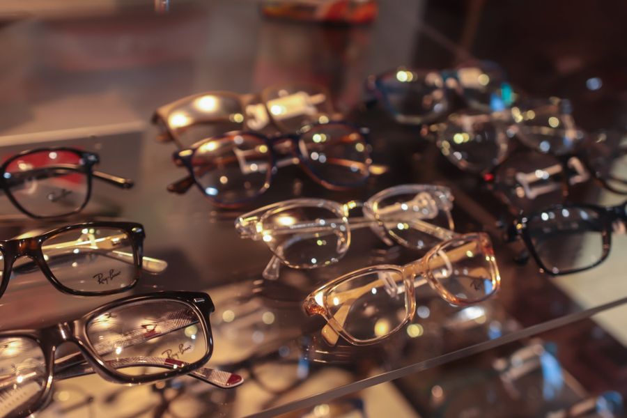 A bunch of glasses are sitting on a glass shelf.