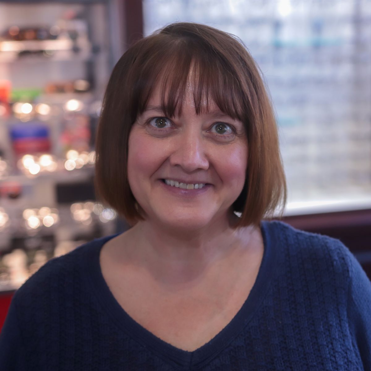 A woman in a blue sweater is smiling for the camera