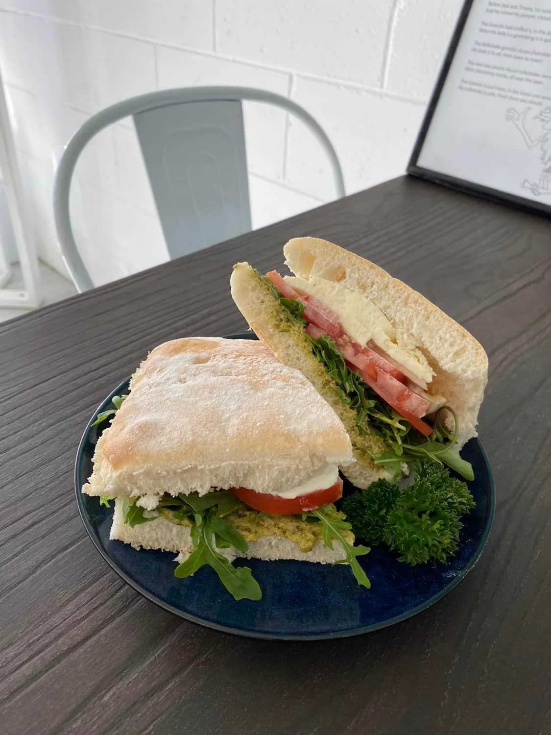 A Sandwich Is Sitting On A Blue Plate On A Wooden Table — Independent Beans in Kirwan, QLD