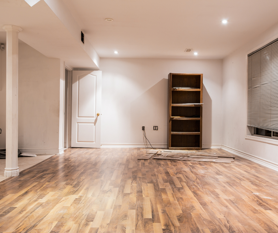 An empty basement with hardwood floors and a bookshelf.