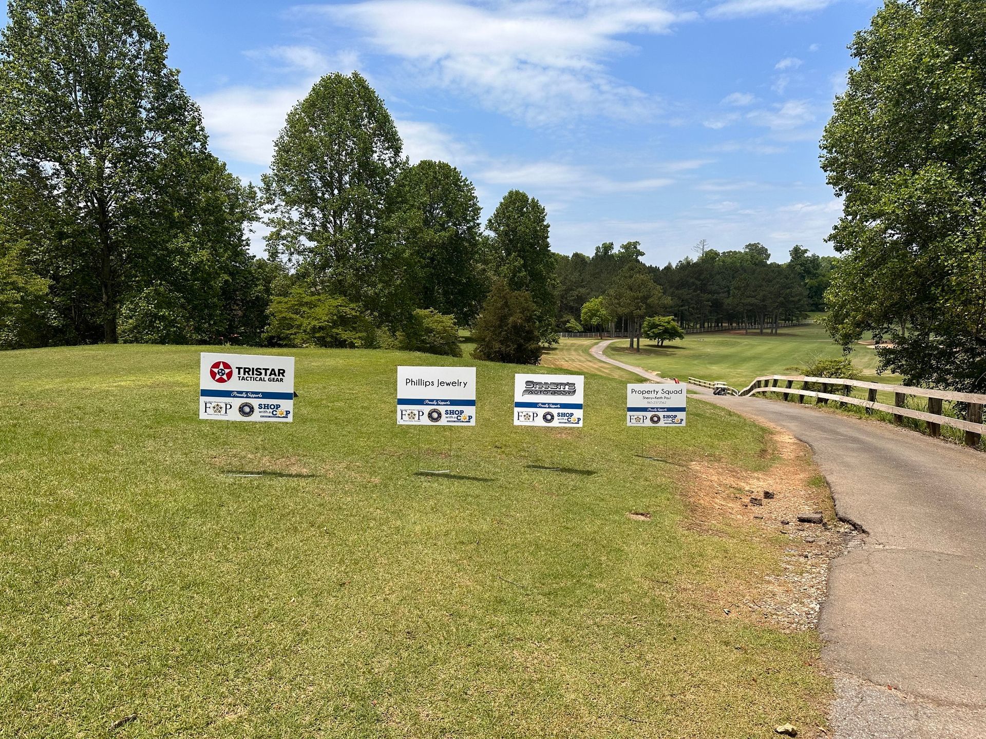 A group of signs are sitting on top of a lush green field next to a road.