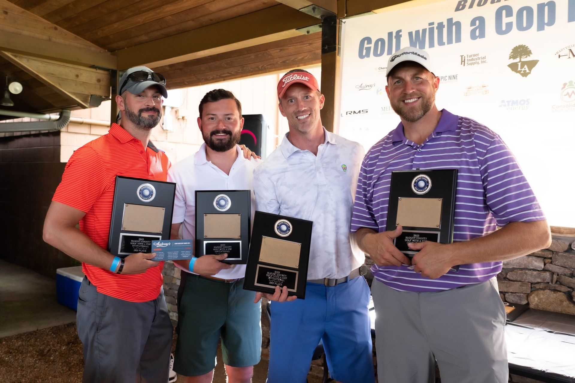A group of men are posing for a picture in front of a sign that says golf with a cop