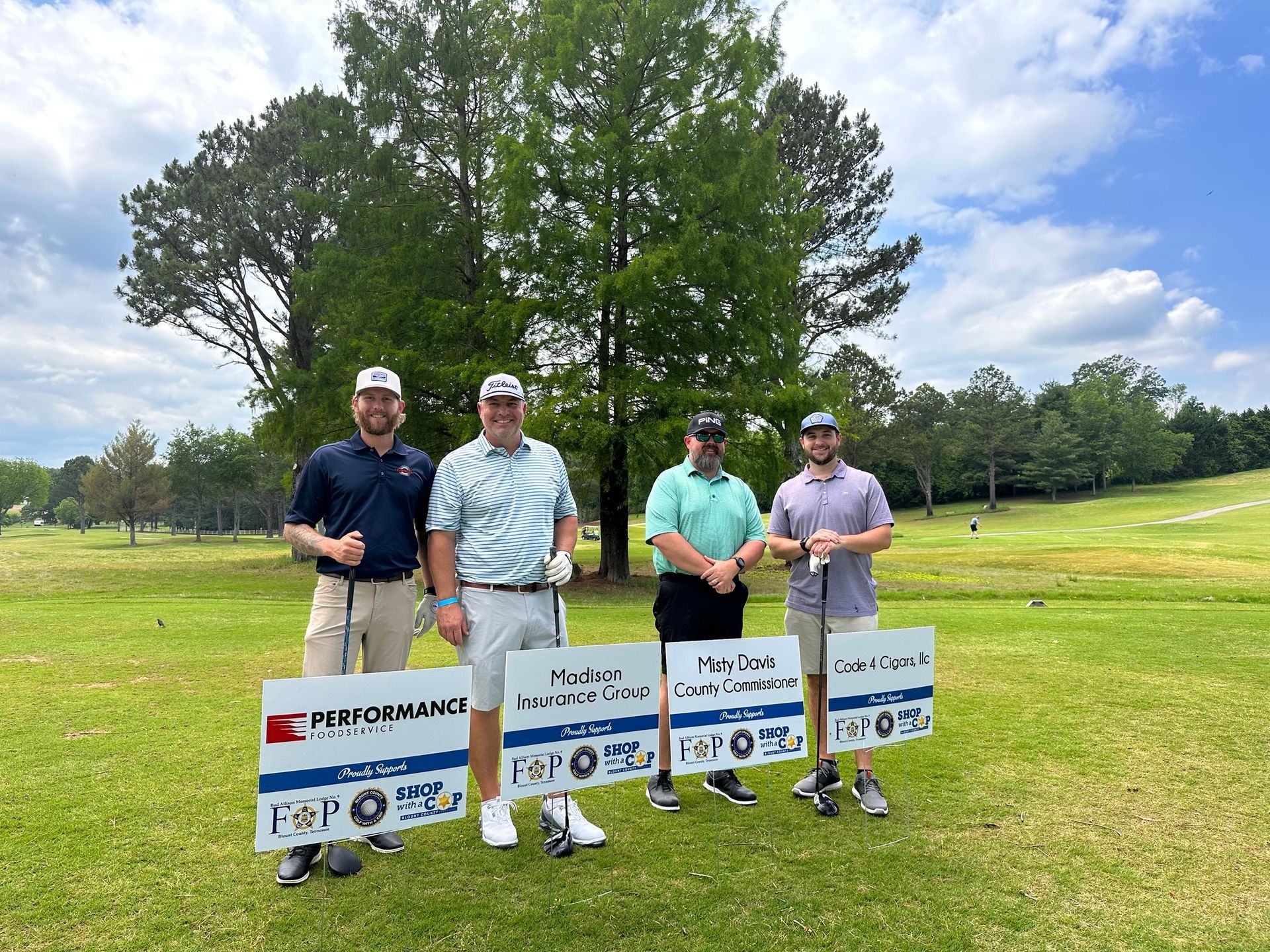 A group of men are standing on a golf course holding golf clubs and signs.
