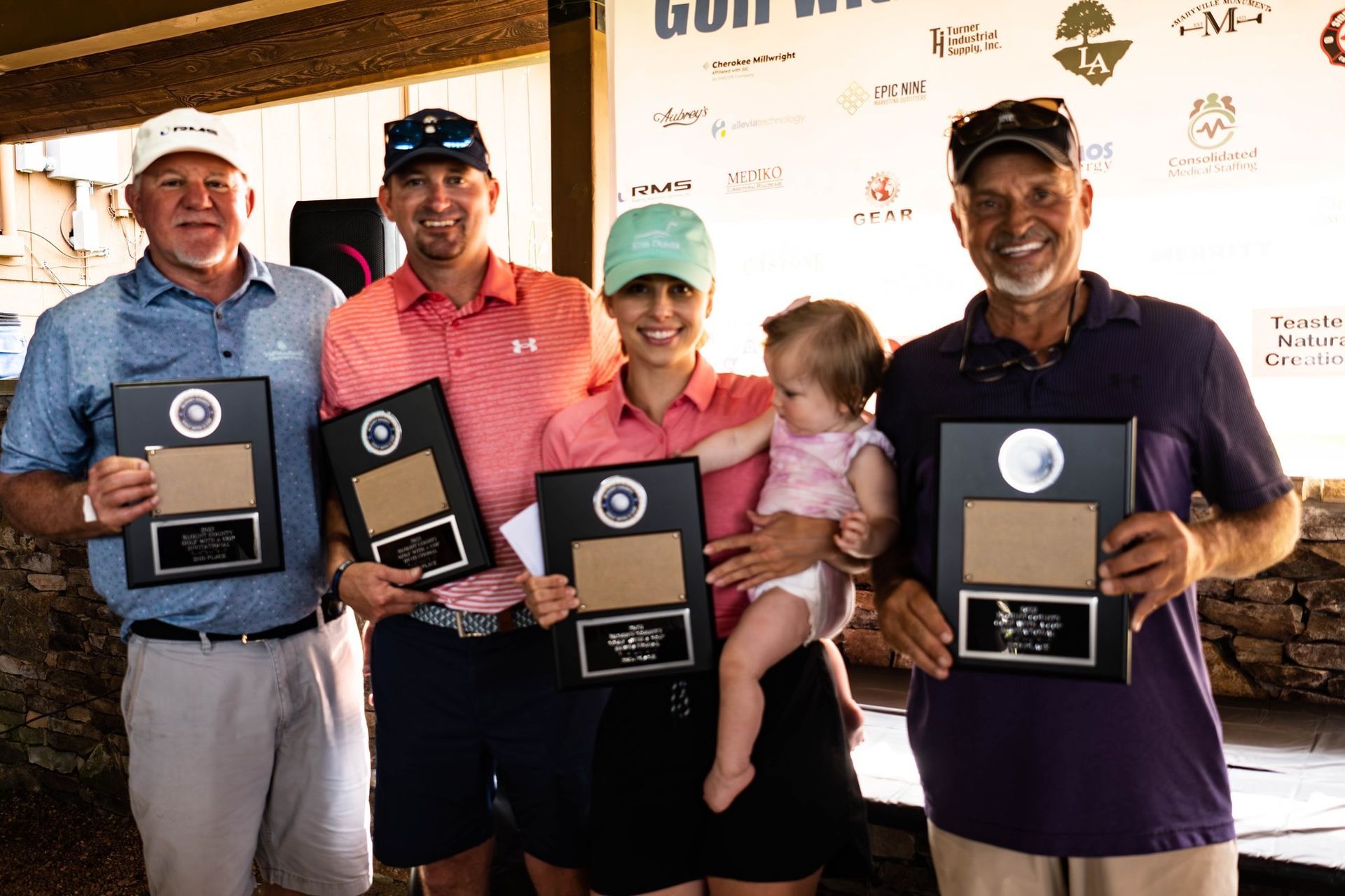 A group of people are standing next to each other holding trophies.