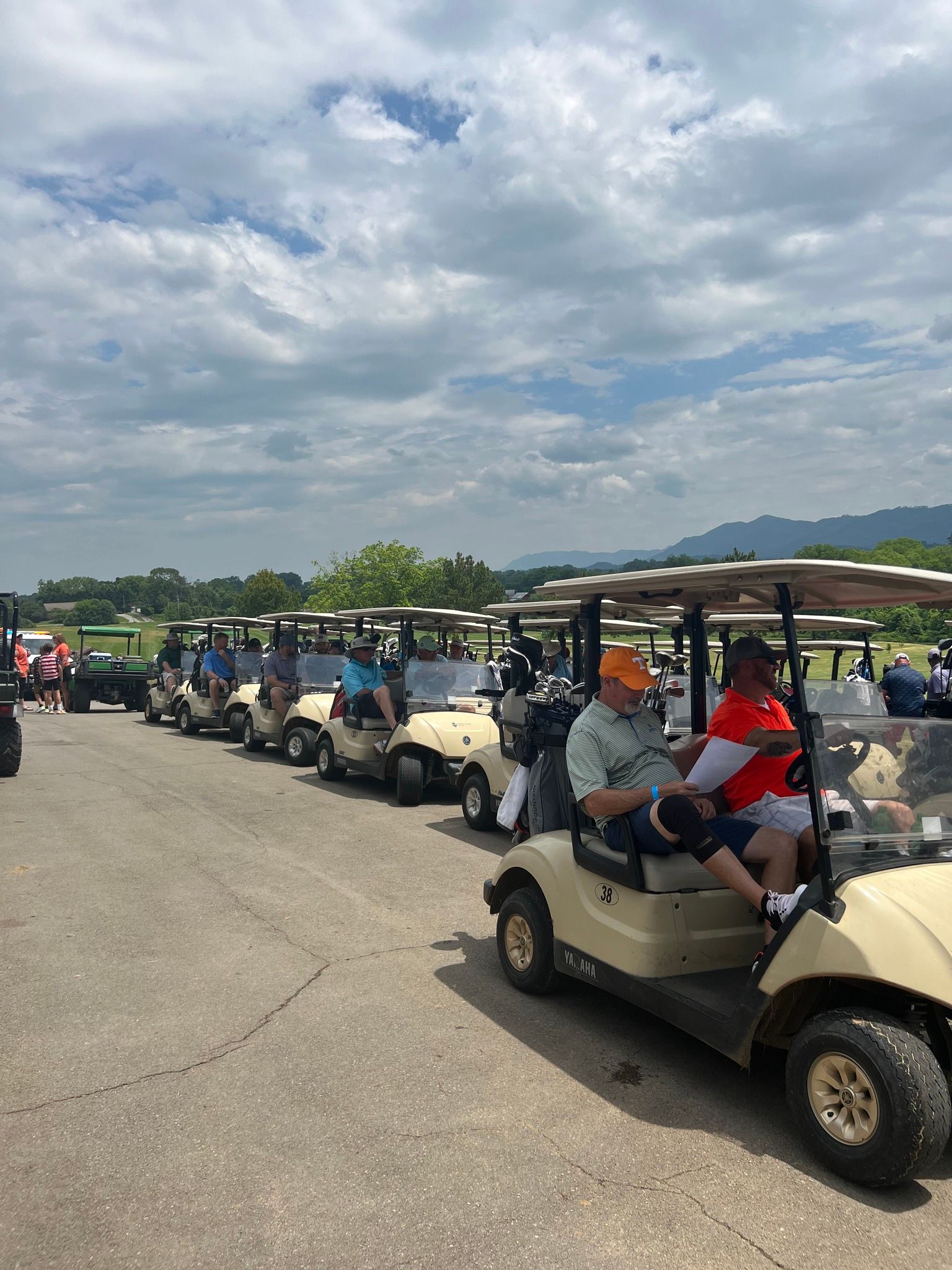 A row of golf carts are parked in a parking lot.