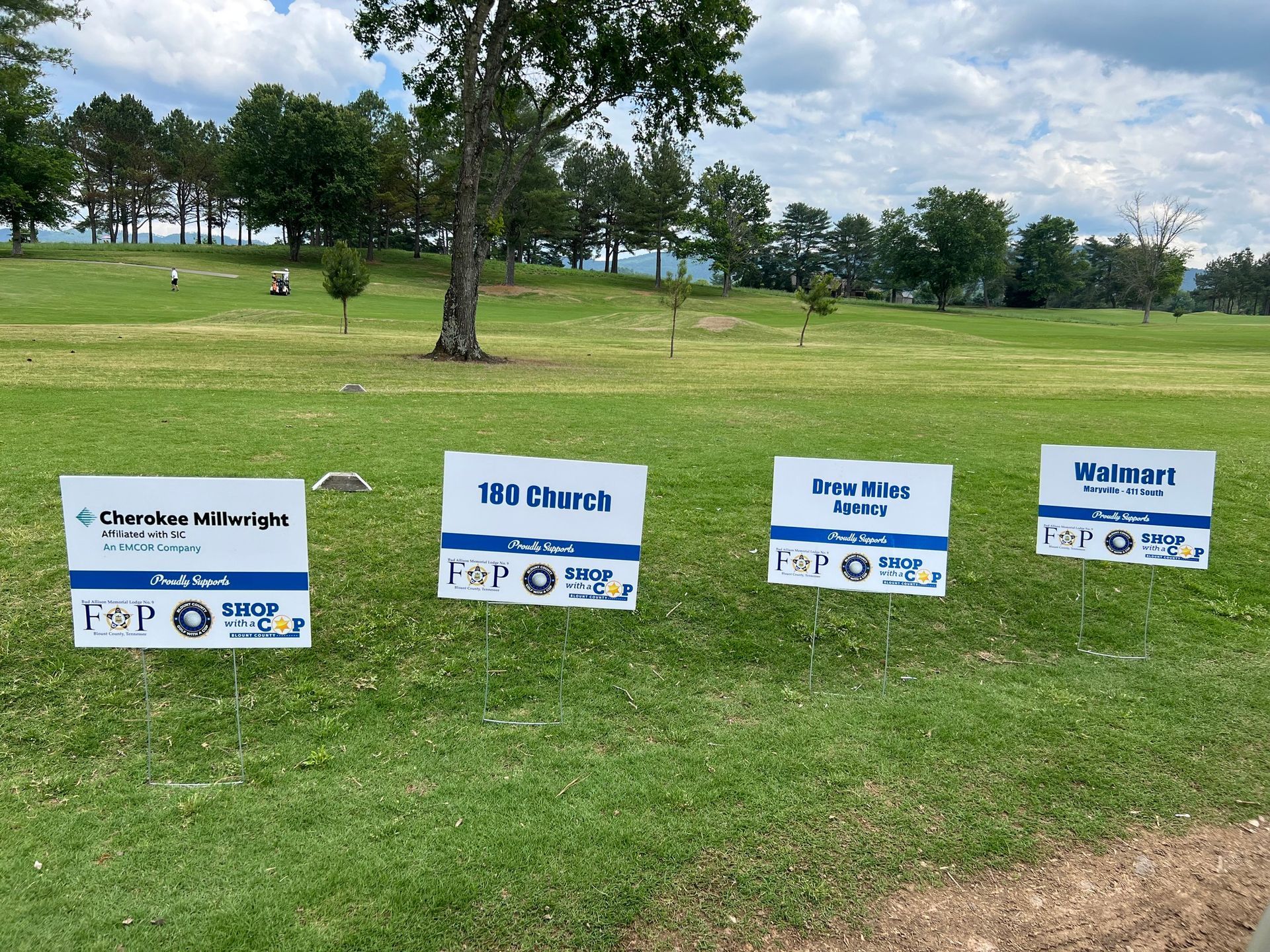 Several signs are lined up in a grassy field