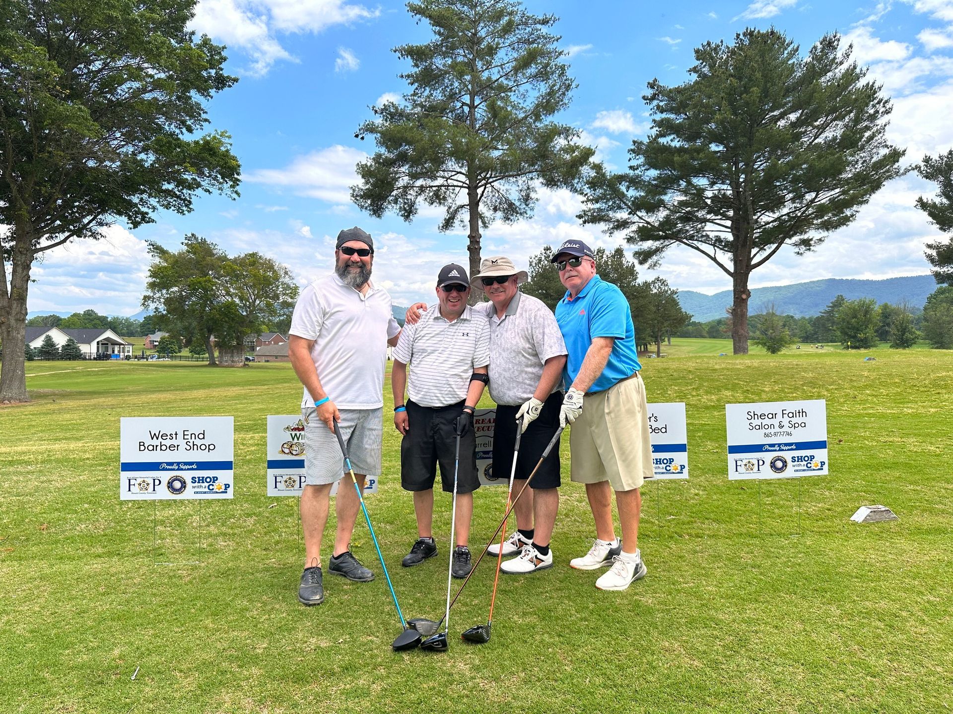 A group of men are standing on a golf course holding golf clubs.