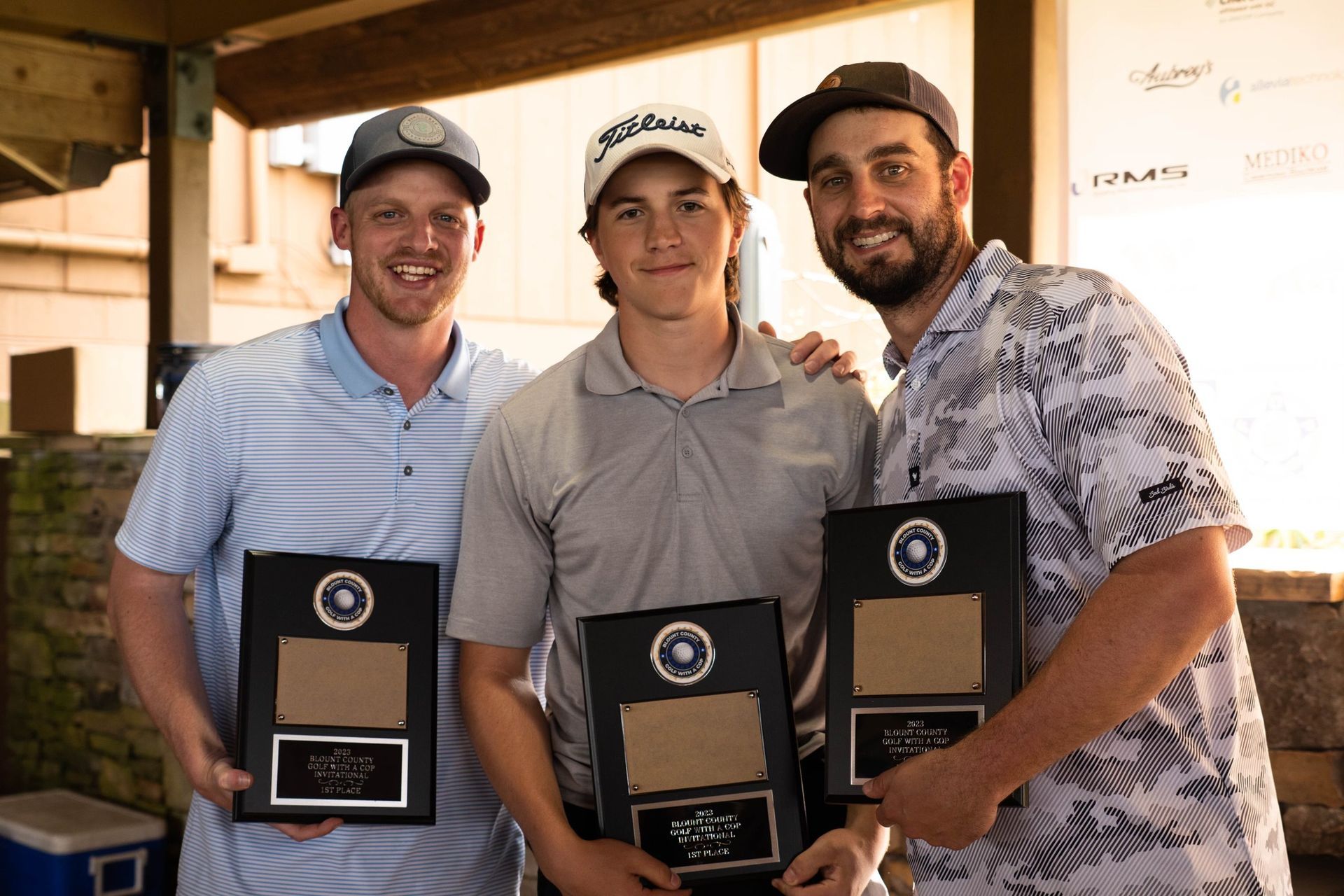 Three men are standing next to each other holding plaques.