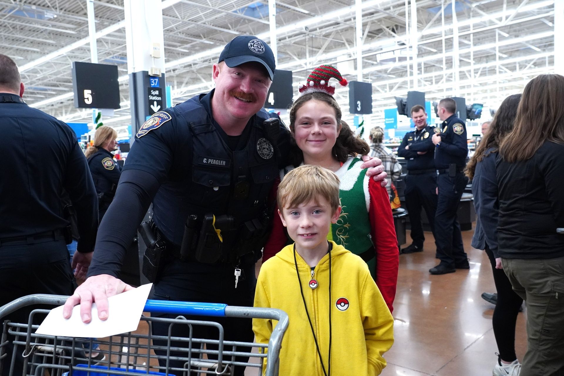 A police officer is posing for a picture with two children in a store.