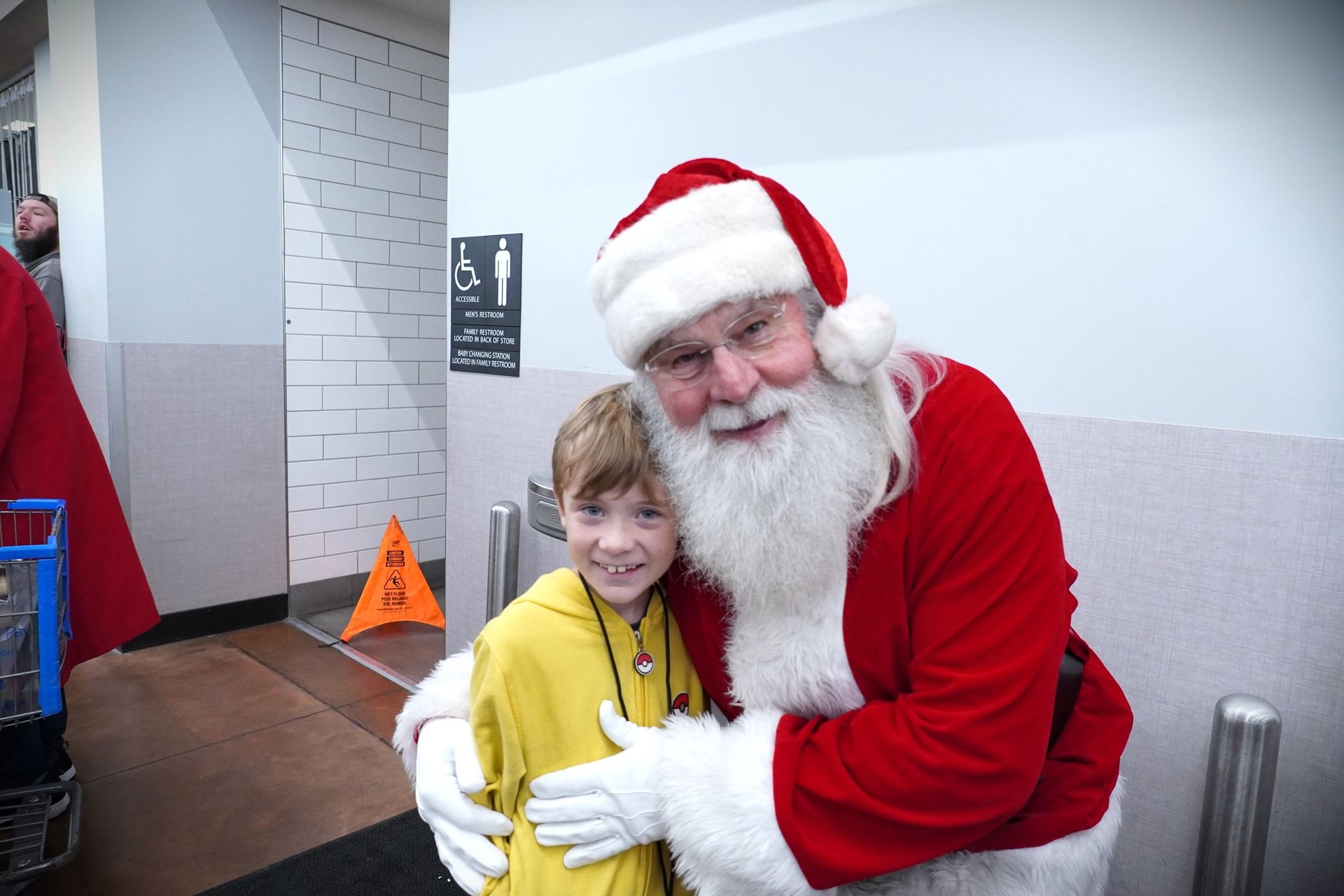 Santa claus is hugging a young boy in a store.