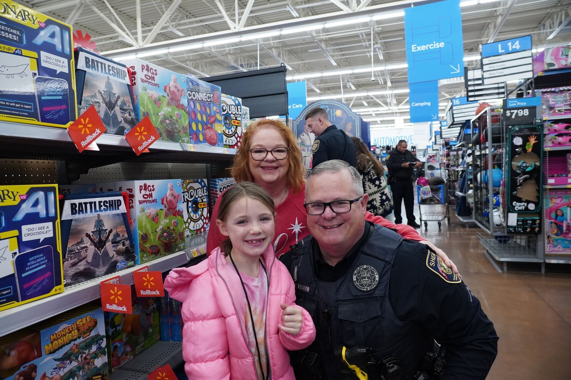 A police officer and a woman are posing for a picture with a little girl in a store.