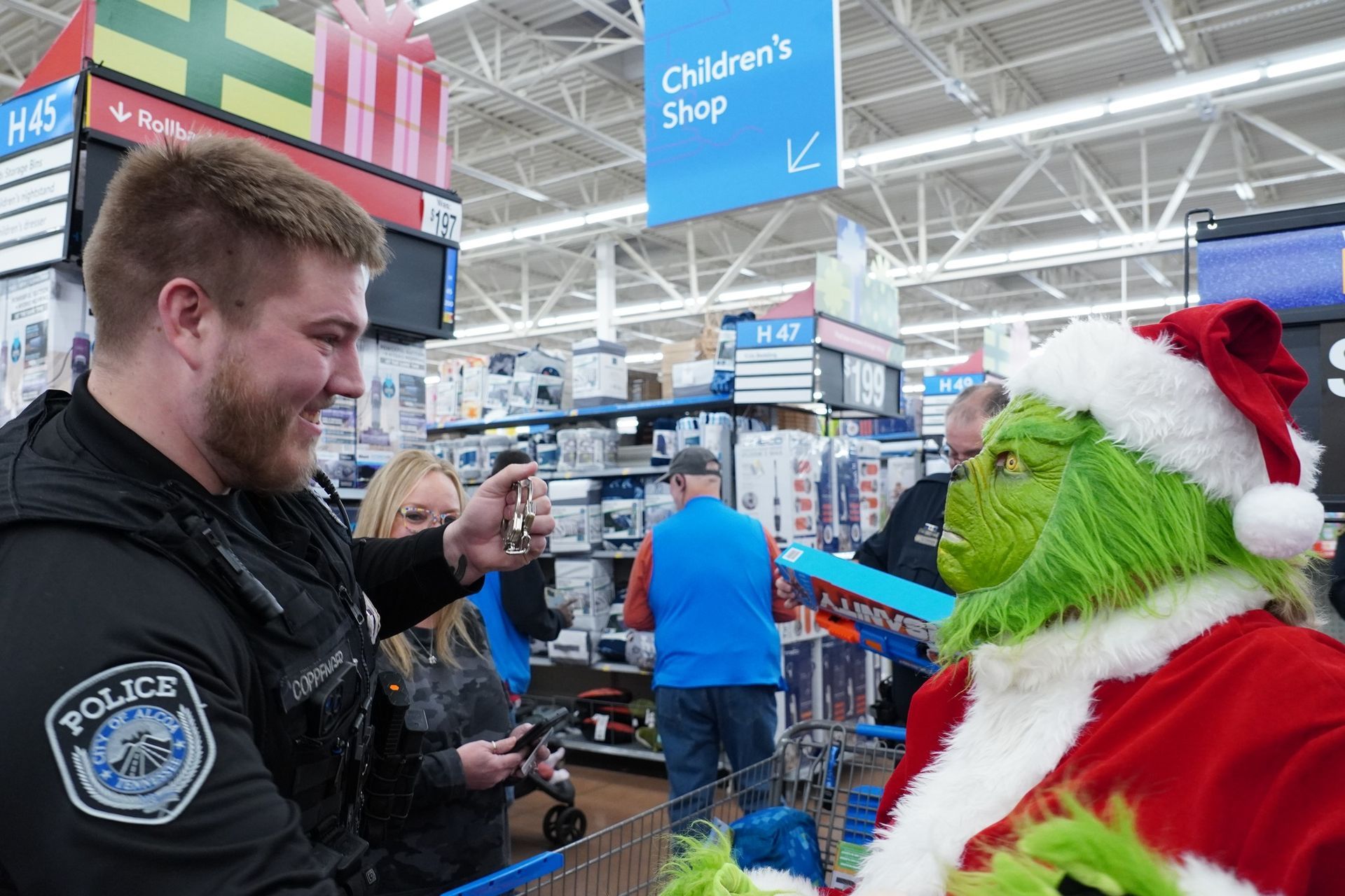 A police officer is taking a picture of a grinch in a store.