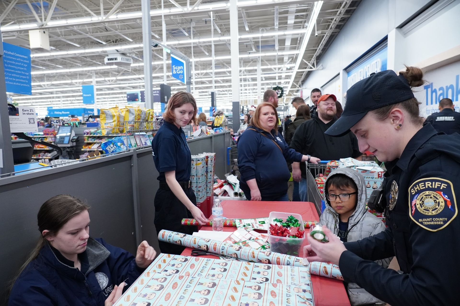 A group of people are wrapping christmas presents in a store.