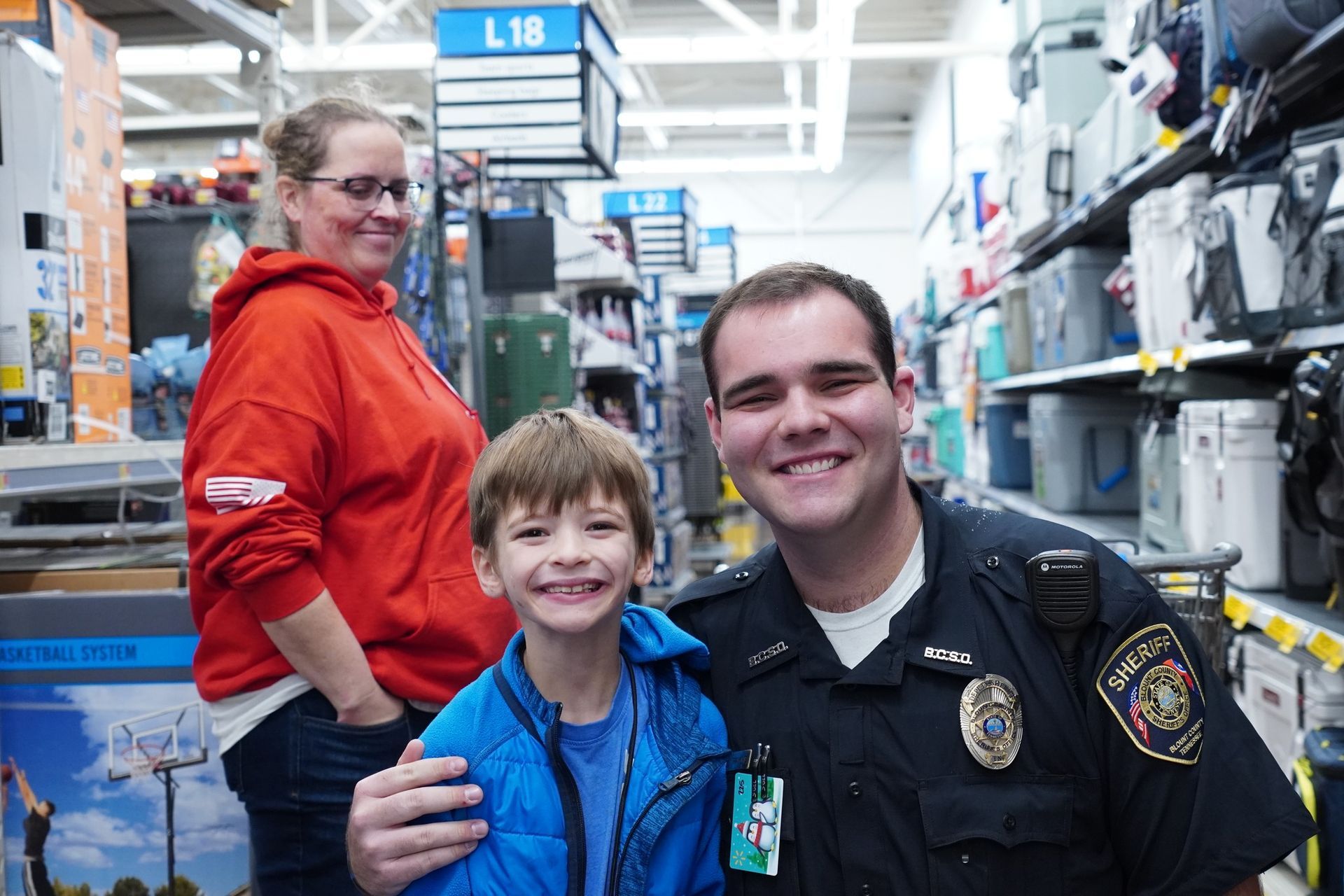 A police officer is posing for a picture with a young boy in a store.