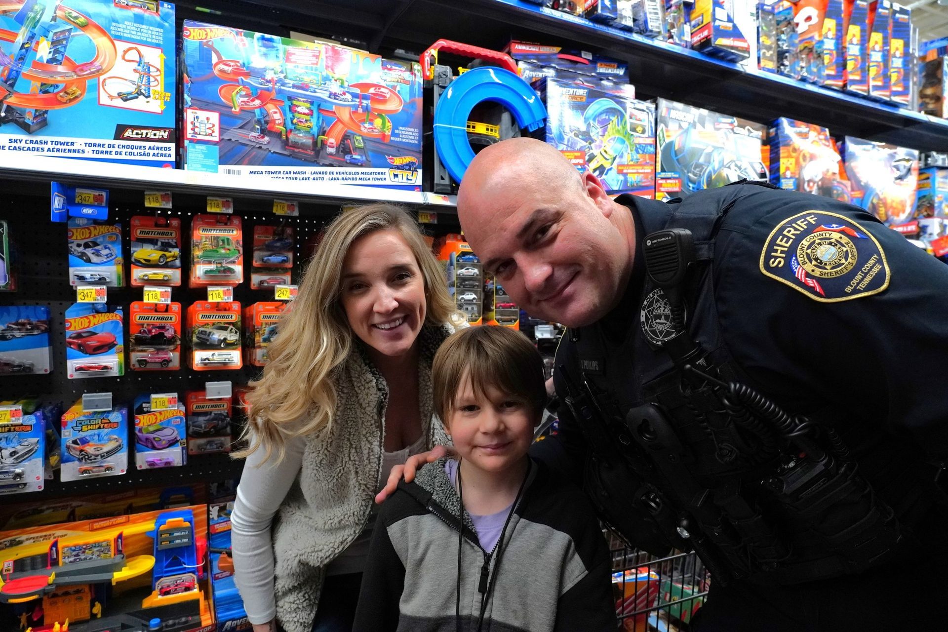 A man in a police uniform is posing for a picture with a boy and a woman