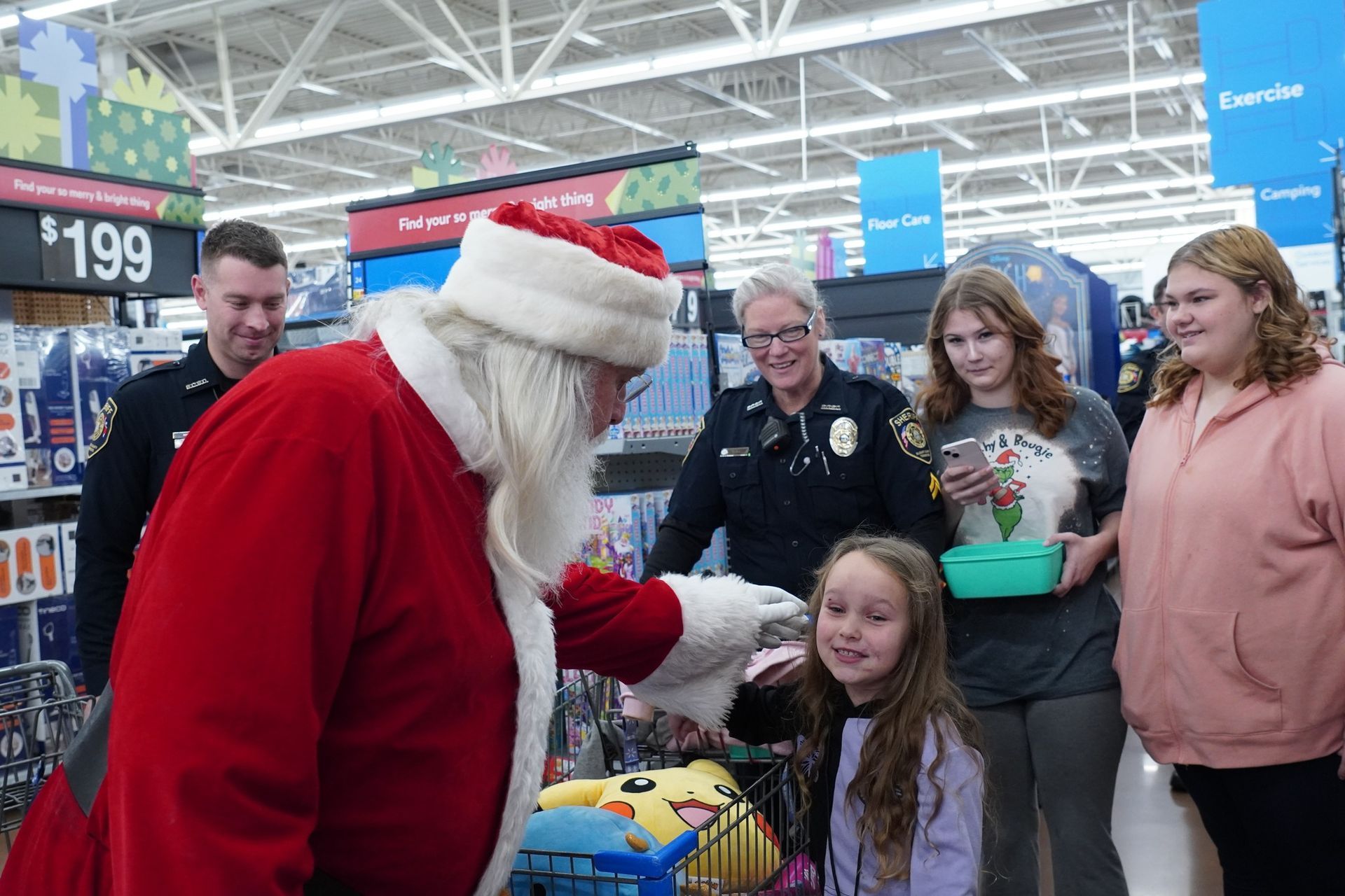 A group of people are standing around santa claus in a store.