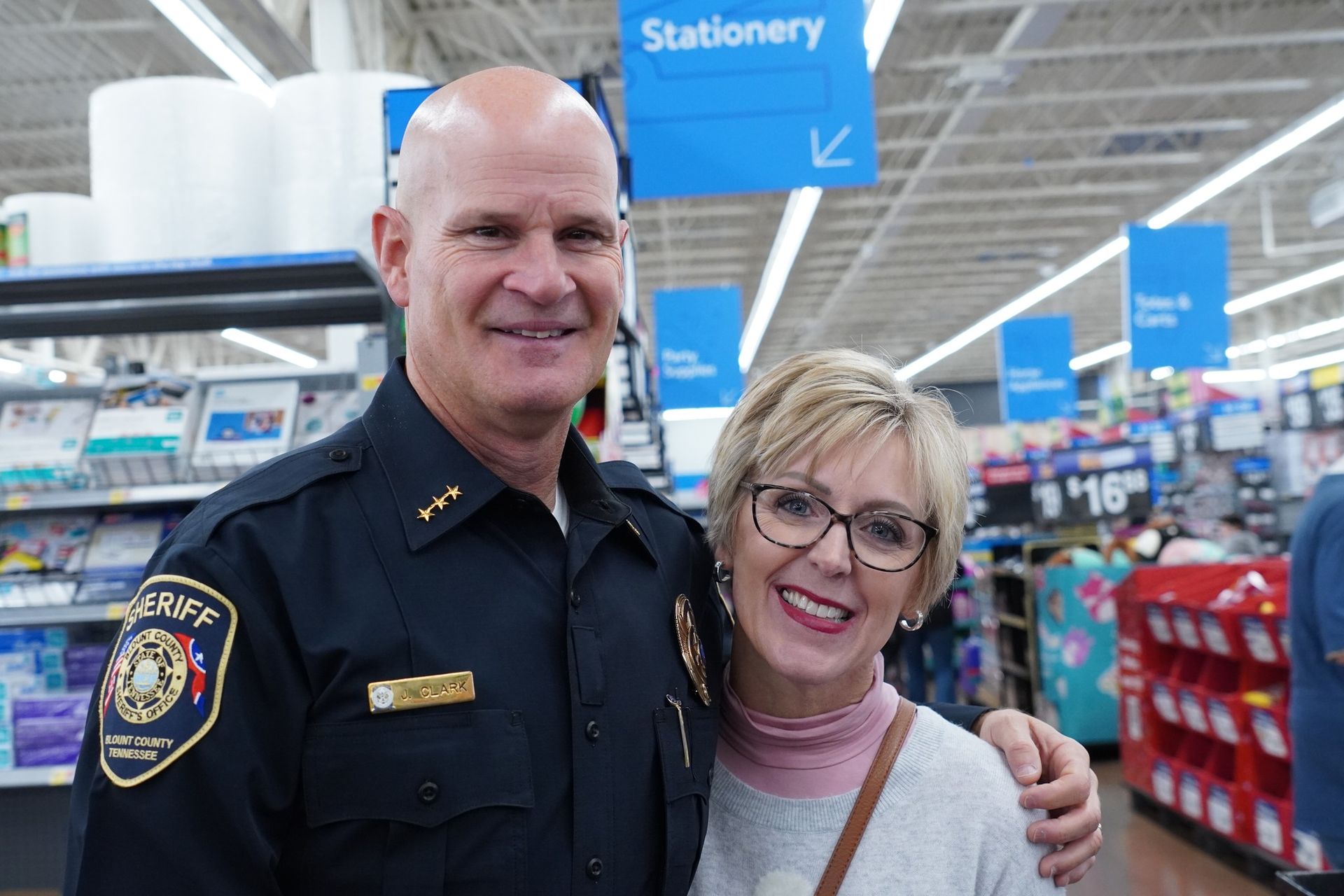 A police officer and a woman are posing for a picture in a store.
