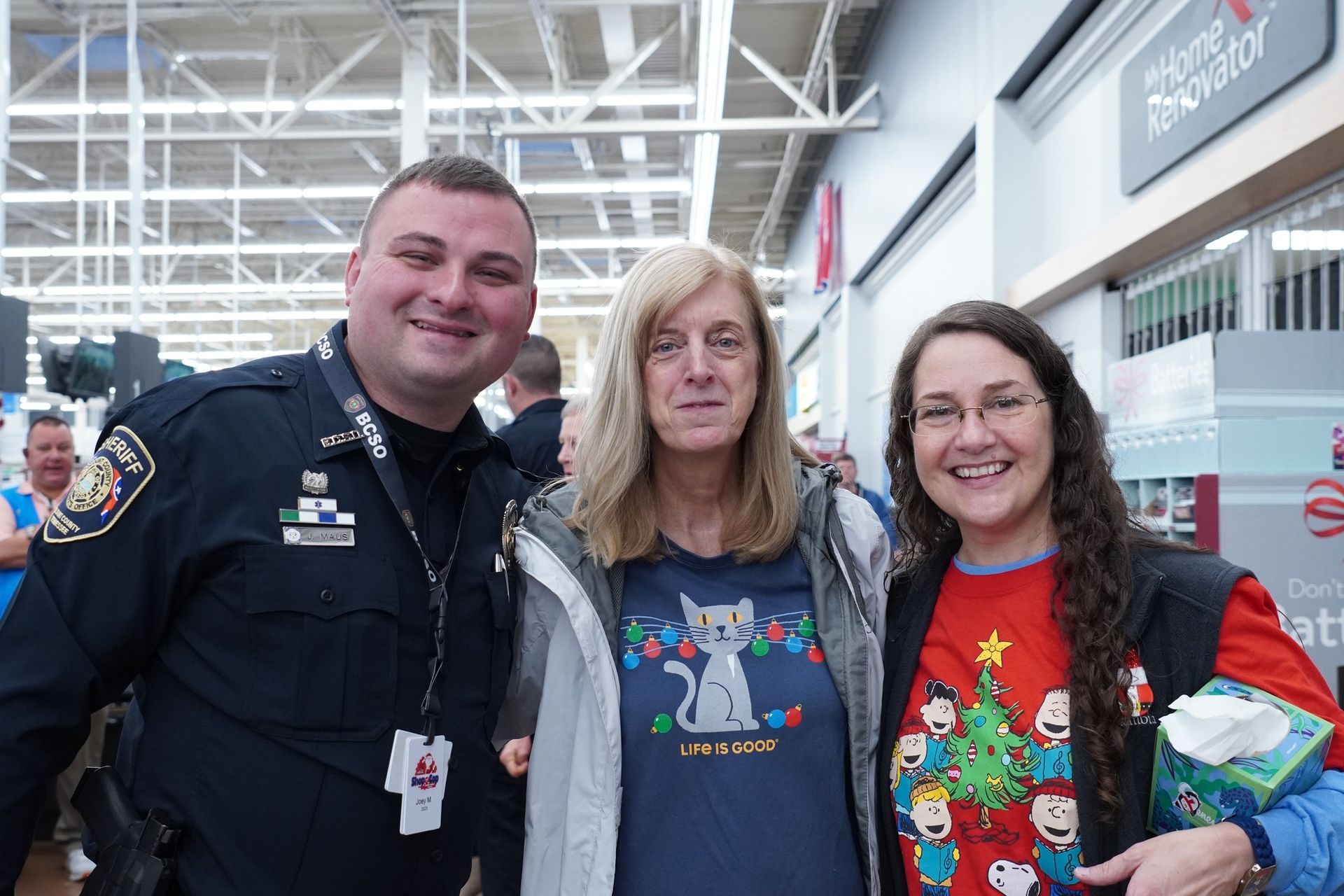 A police officer and two women are posing for a picture in a store.