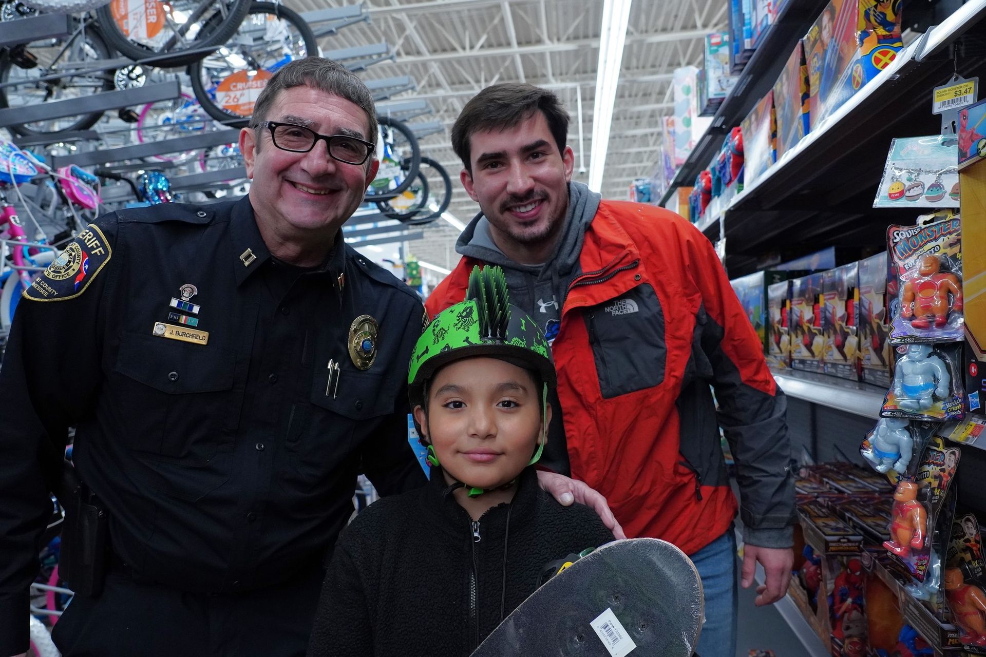 A boy wearing a helmet is posing for a picture with two men in a store.