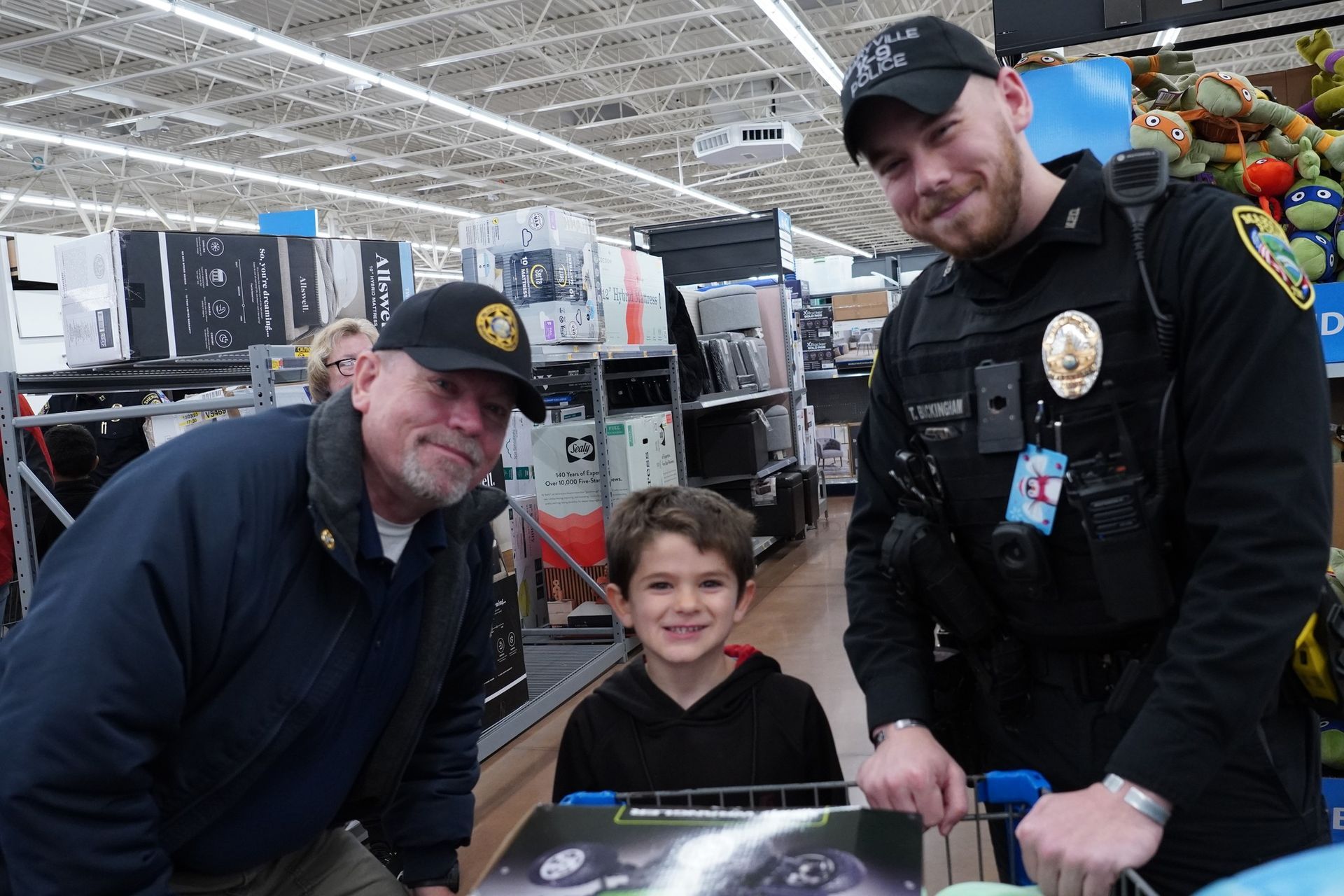 Two police officers posing with little boy while shopping.