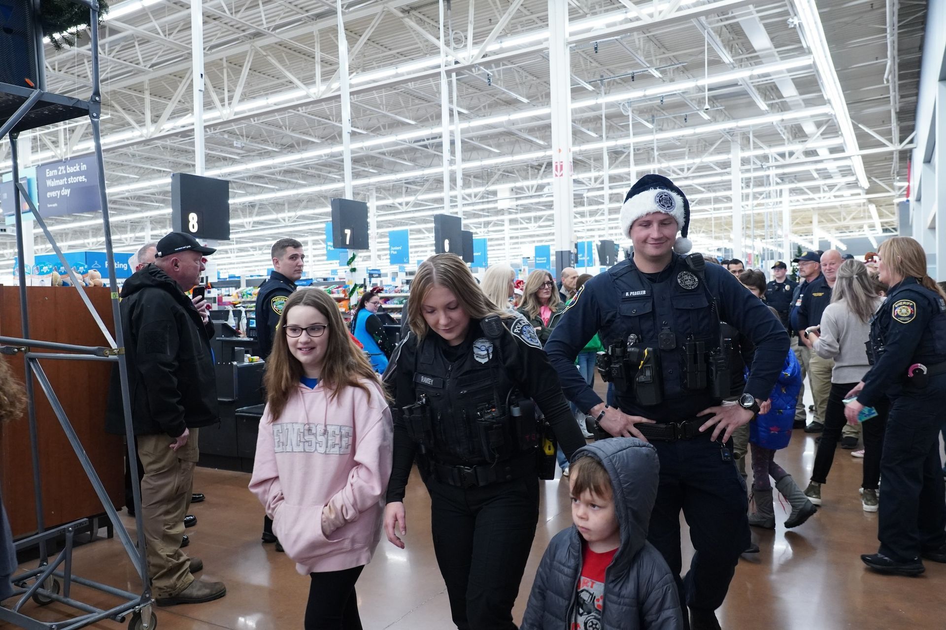 A group of police officers are walking with a child in a store.