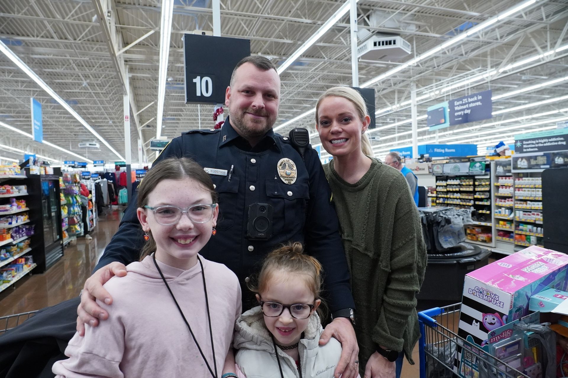 A police officer is posing for a picture with a family in a store.