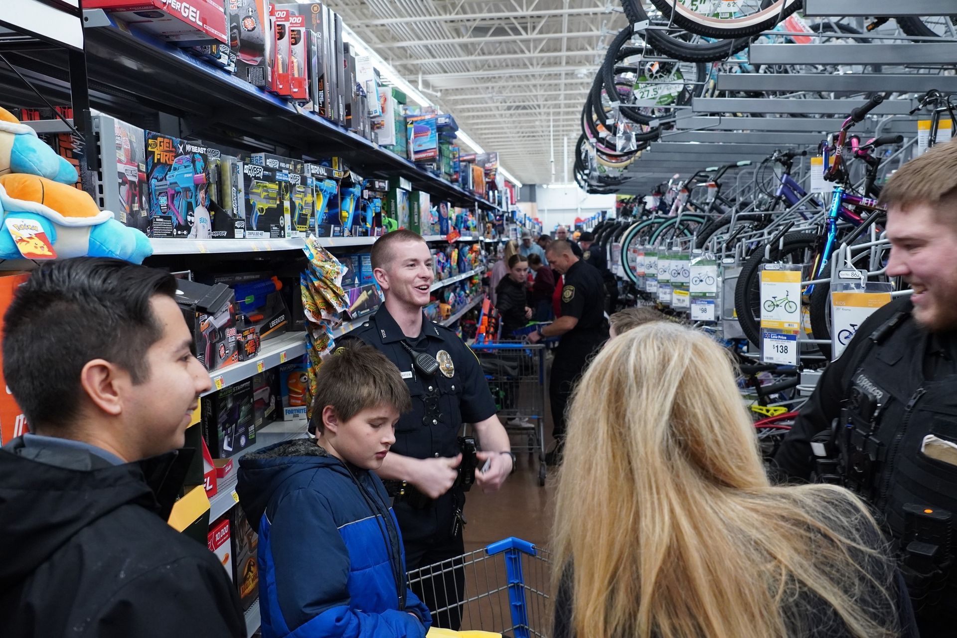 A group of people are standing in a store talking to each other.