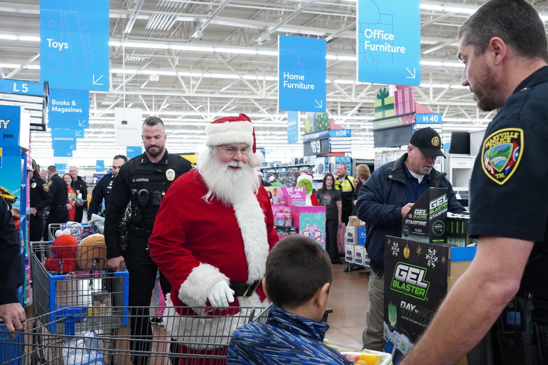 Santa claus is talking to a boy in a shopping cart in a store.