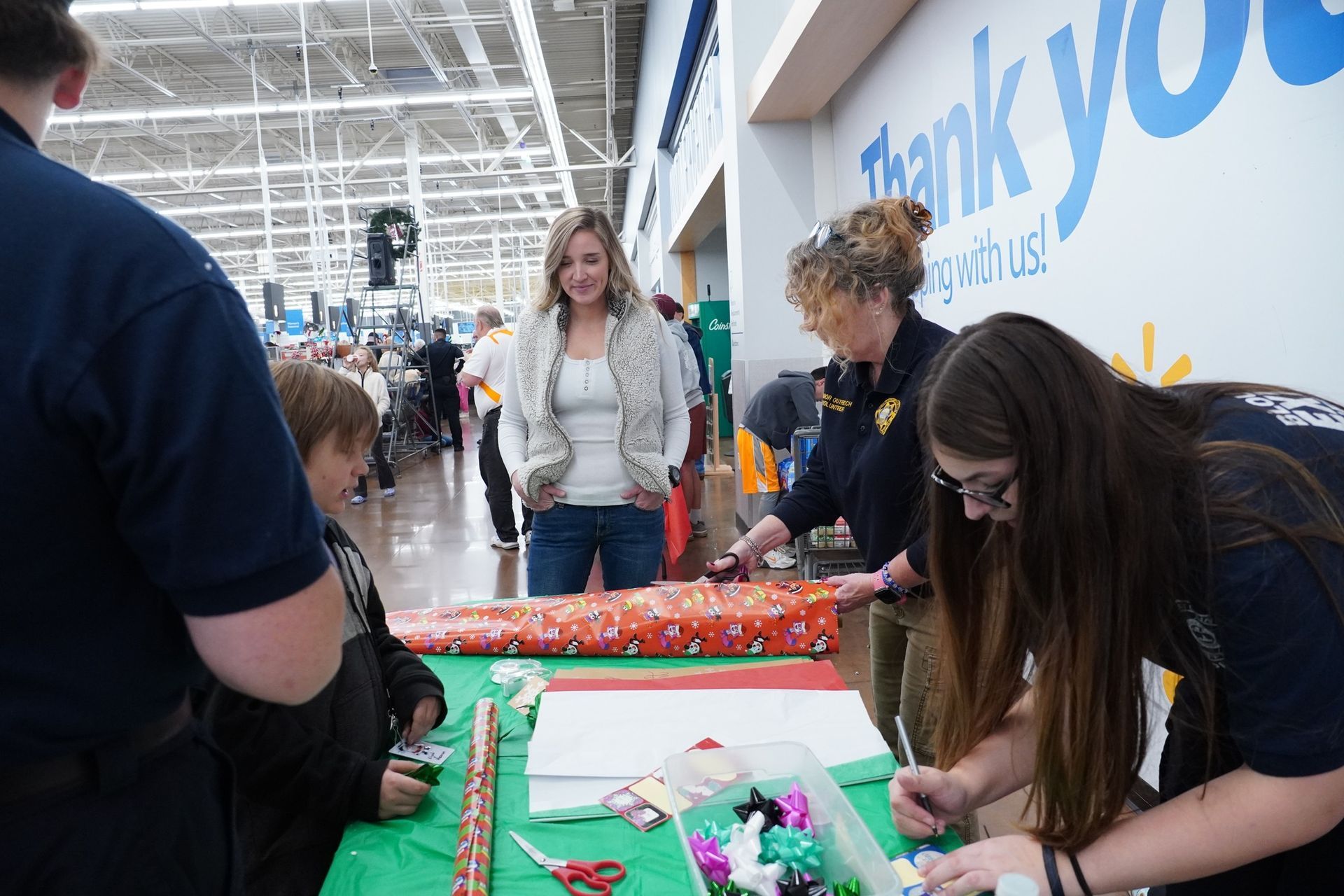 A group of people are wrapping christmas presents in a store.