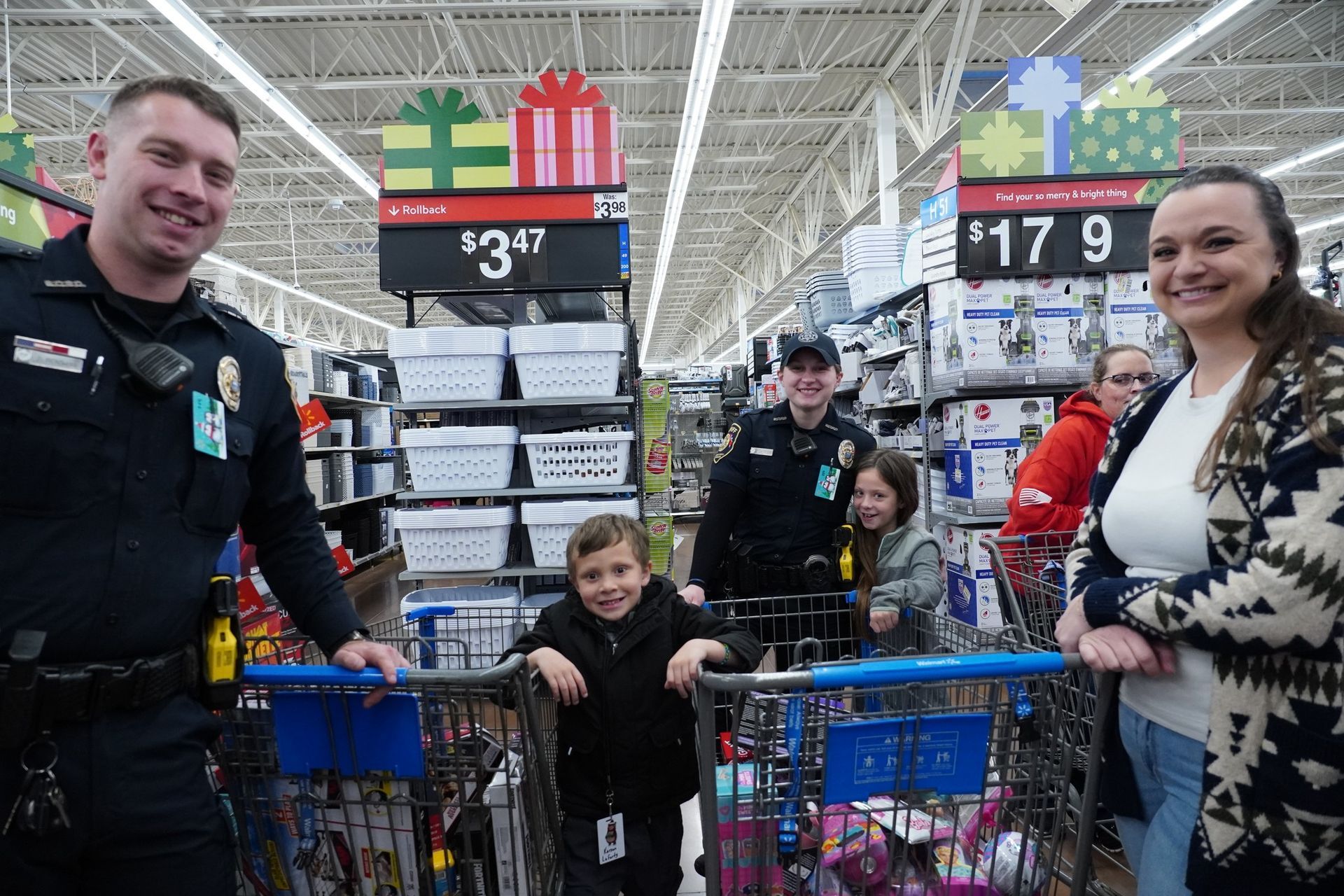 A group of people are standing next to a shopping cart in a store.