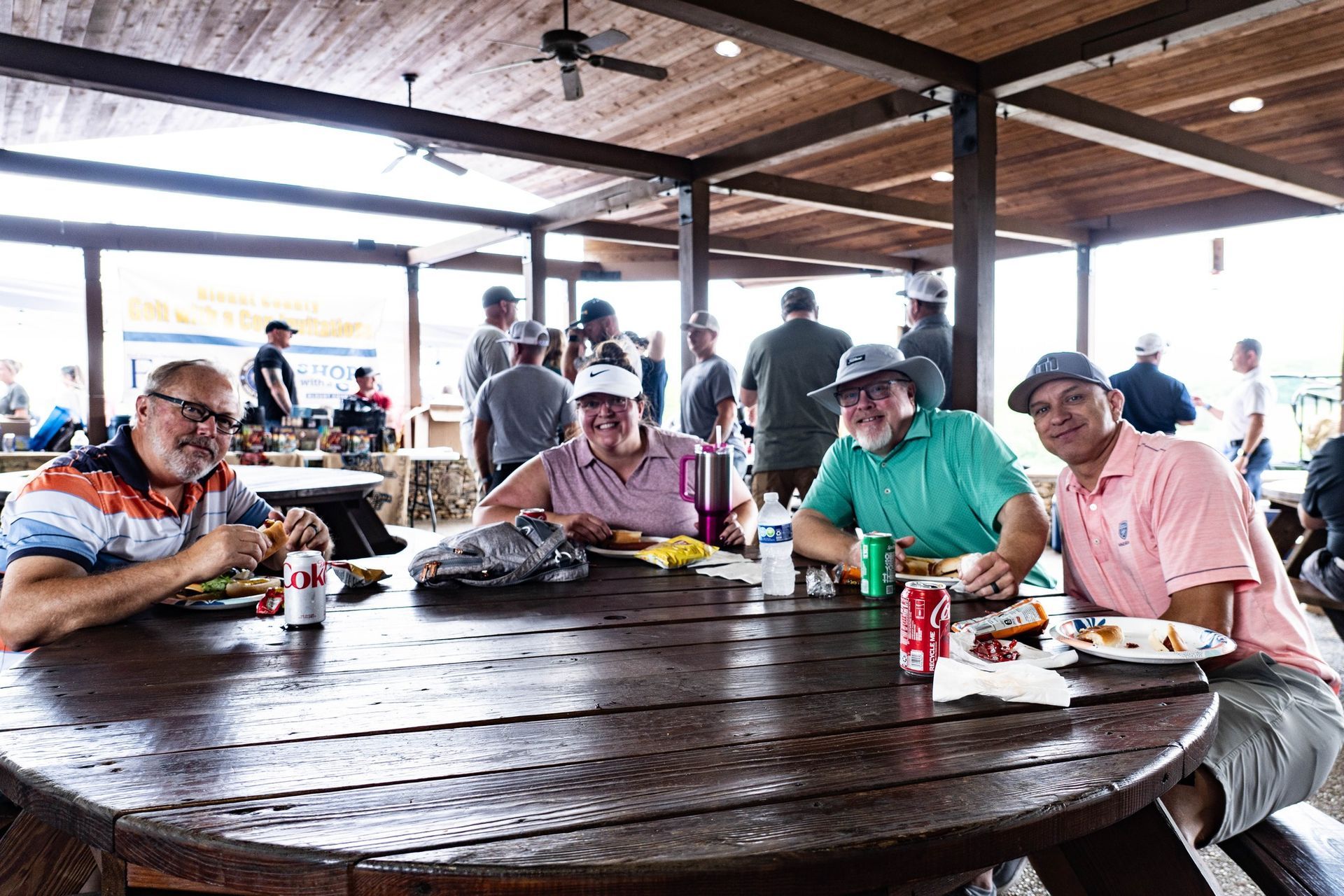 A group of people are sitting at a picnic table eating food.