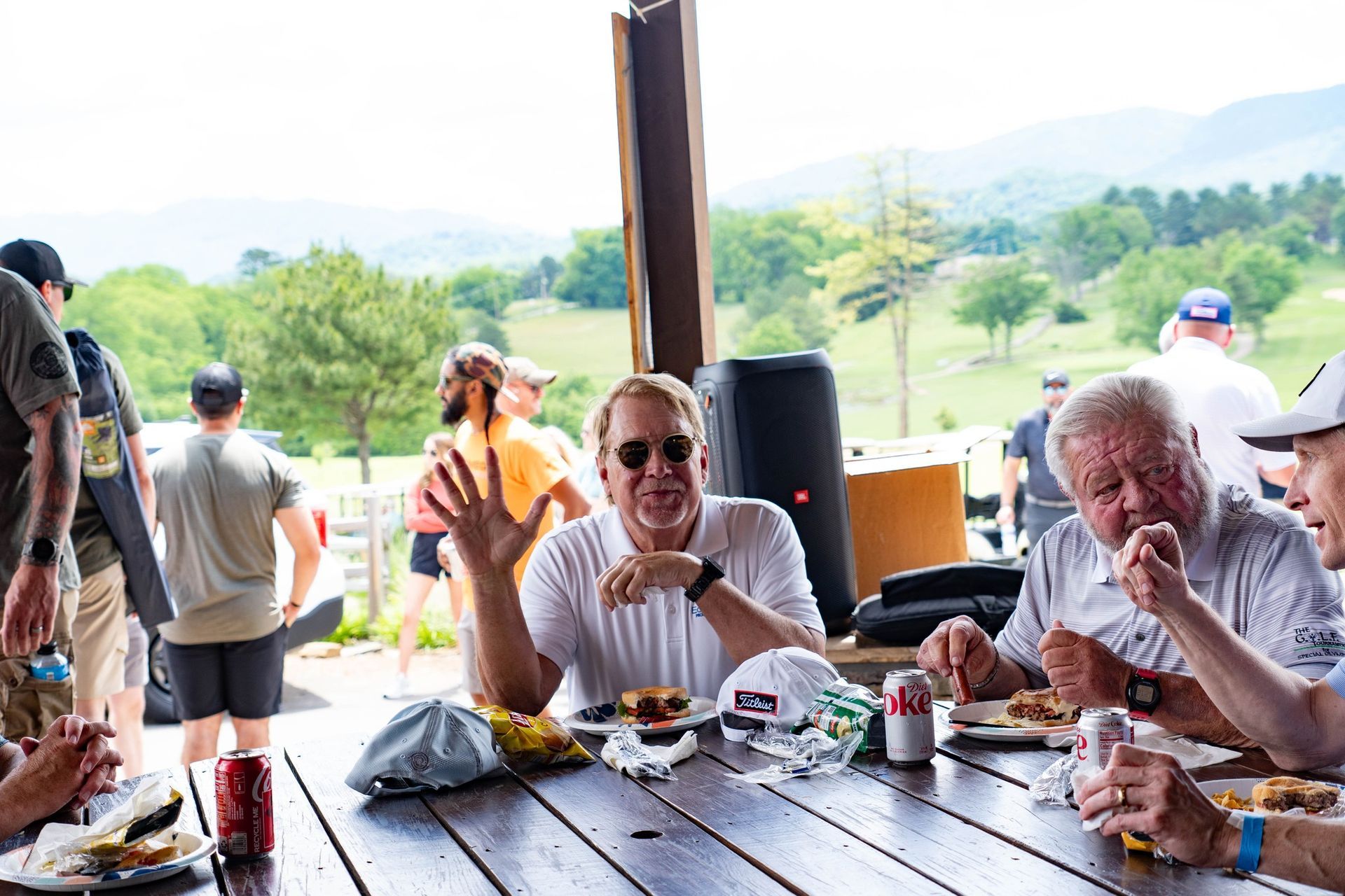 A group of people are sitting at a picnic table eating food.