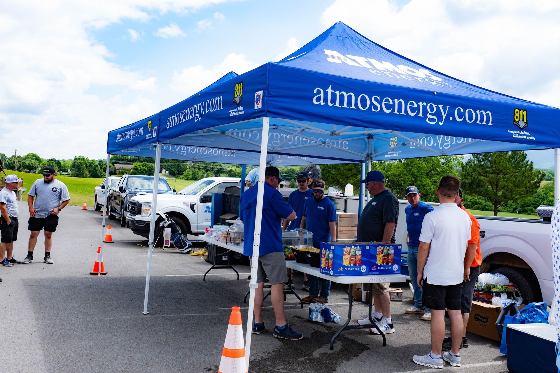 A group of people standing under a tent that says atmosenergy.com