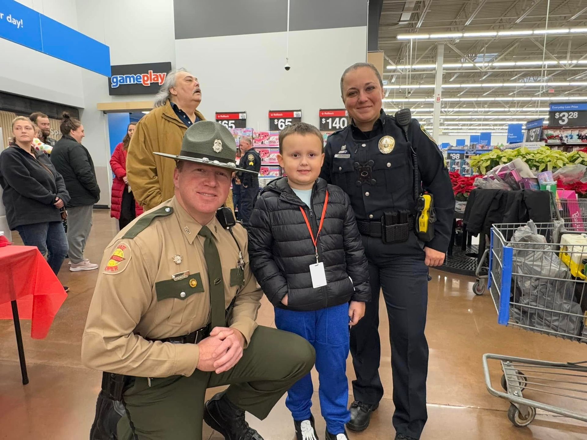 A group of police officers are posing for a picture with a young boy in a store.