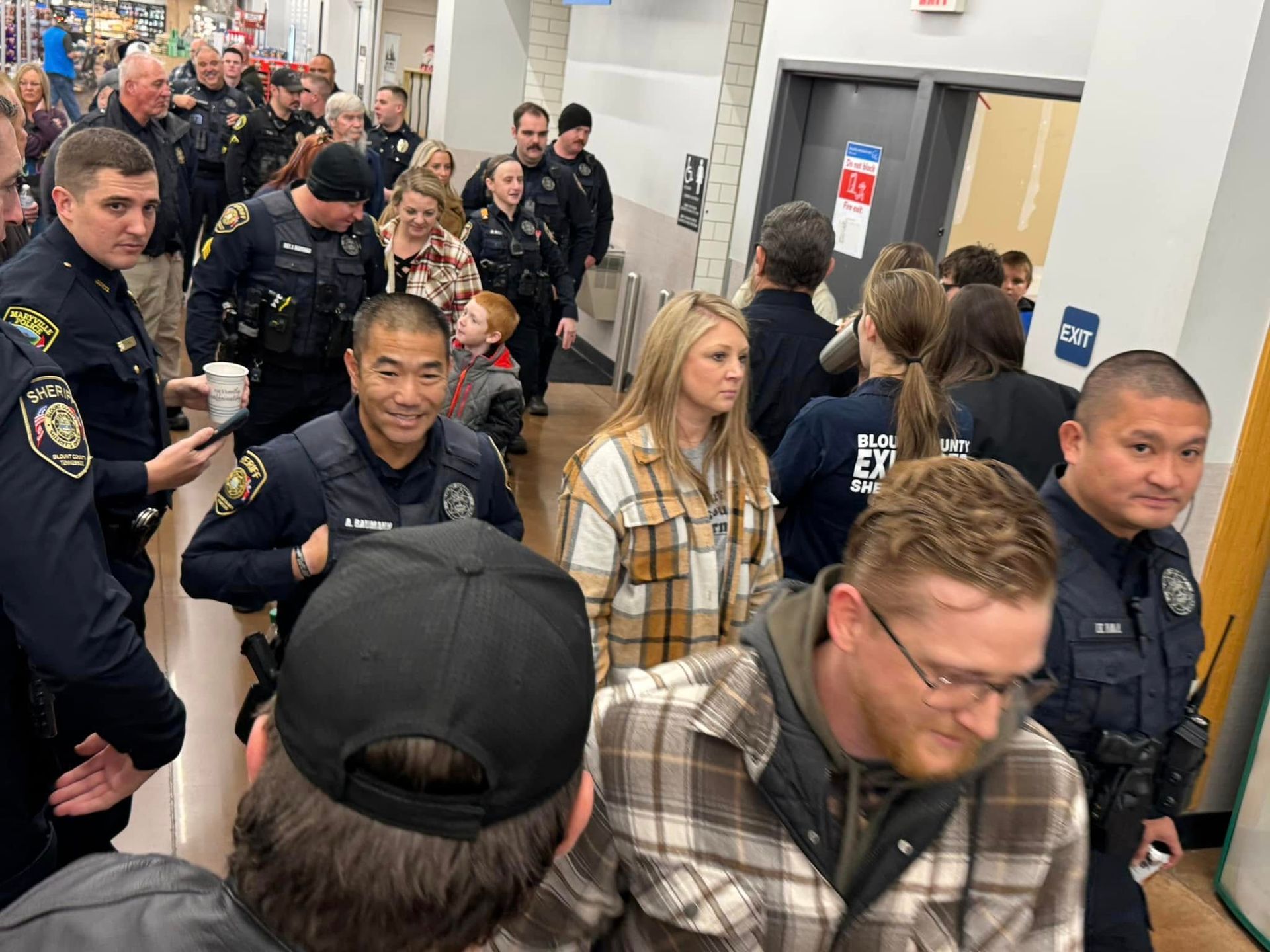 A large group of people are standing in a hallway.