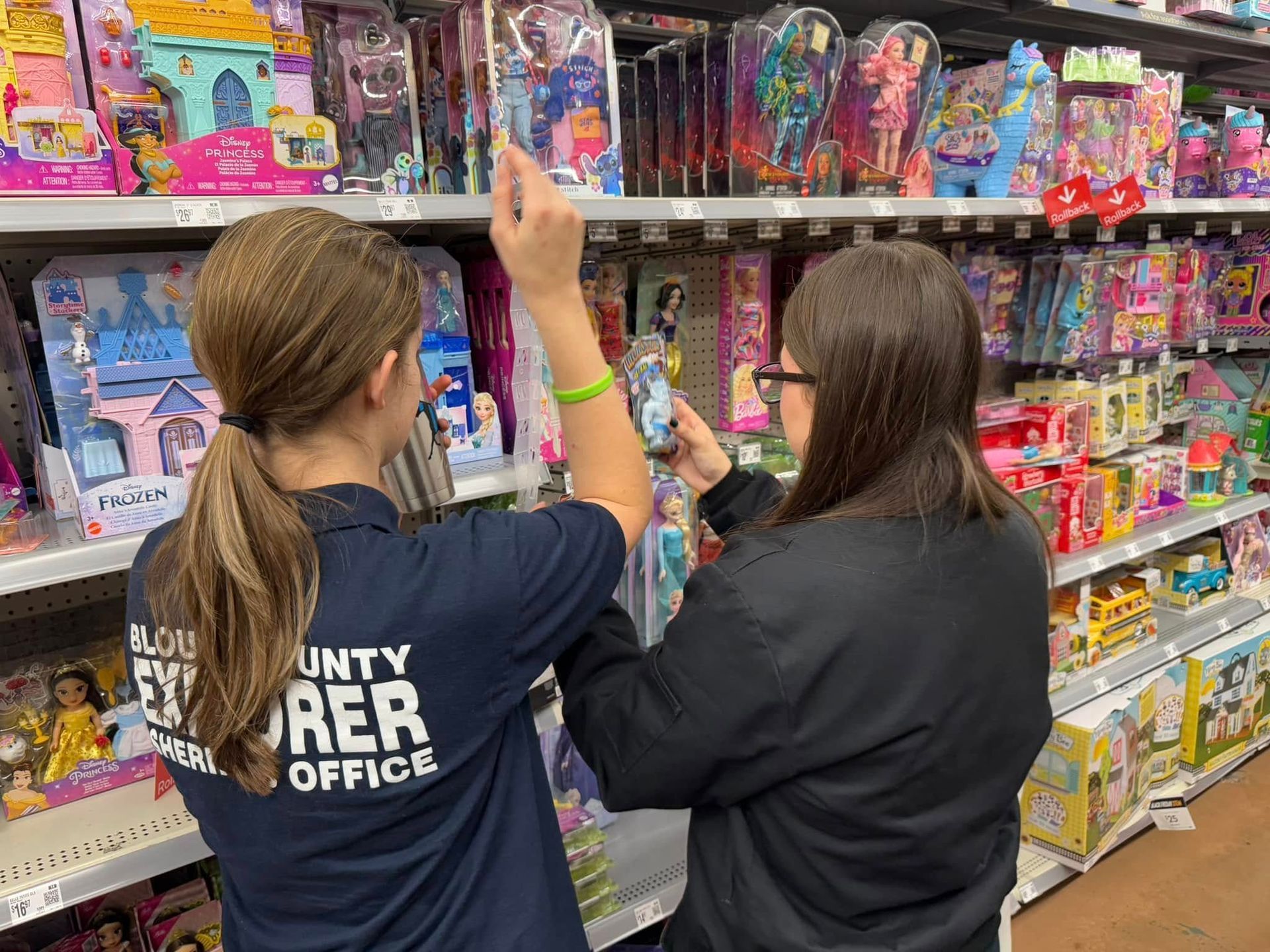 Two women are looking at toys on a shelf in a store.
