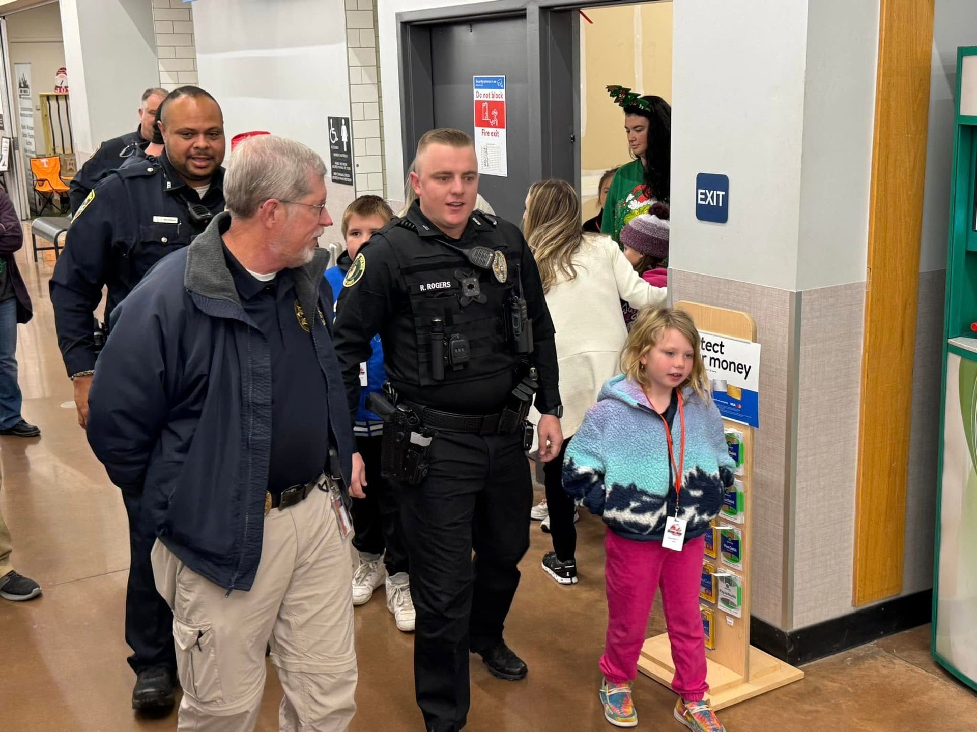 A group of police officers are walking with a little girl in a store.