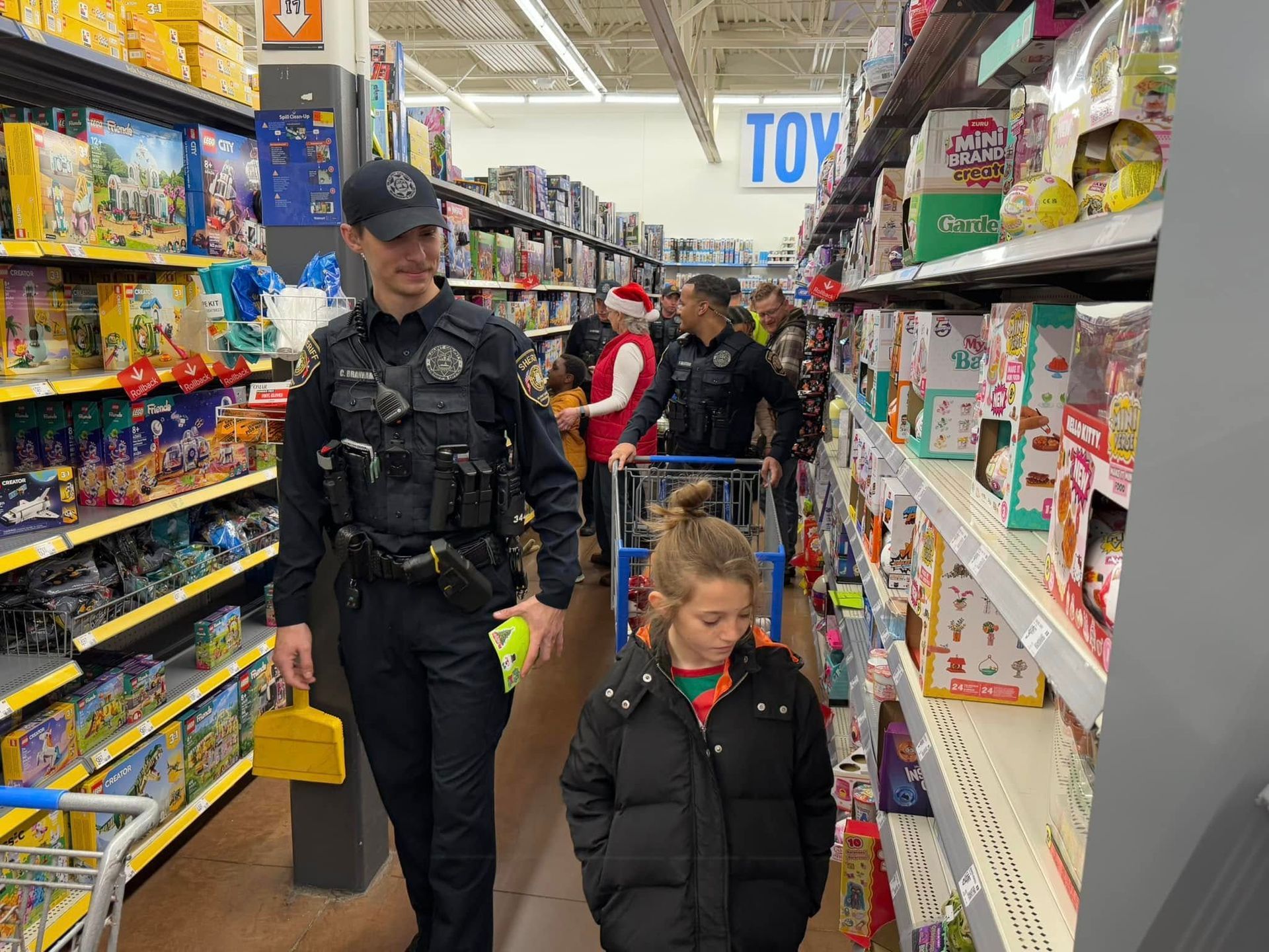 A police officer is walking with a child in a toy section of a store.