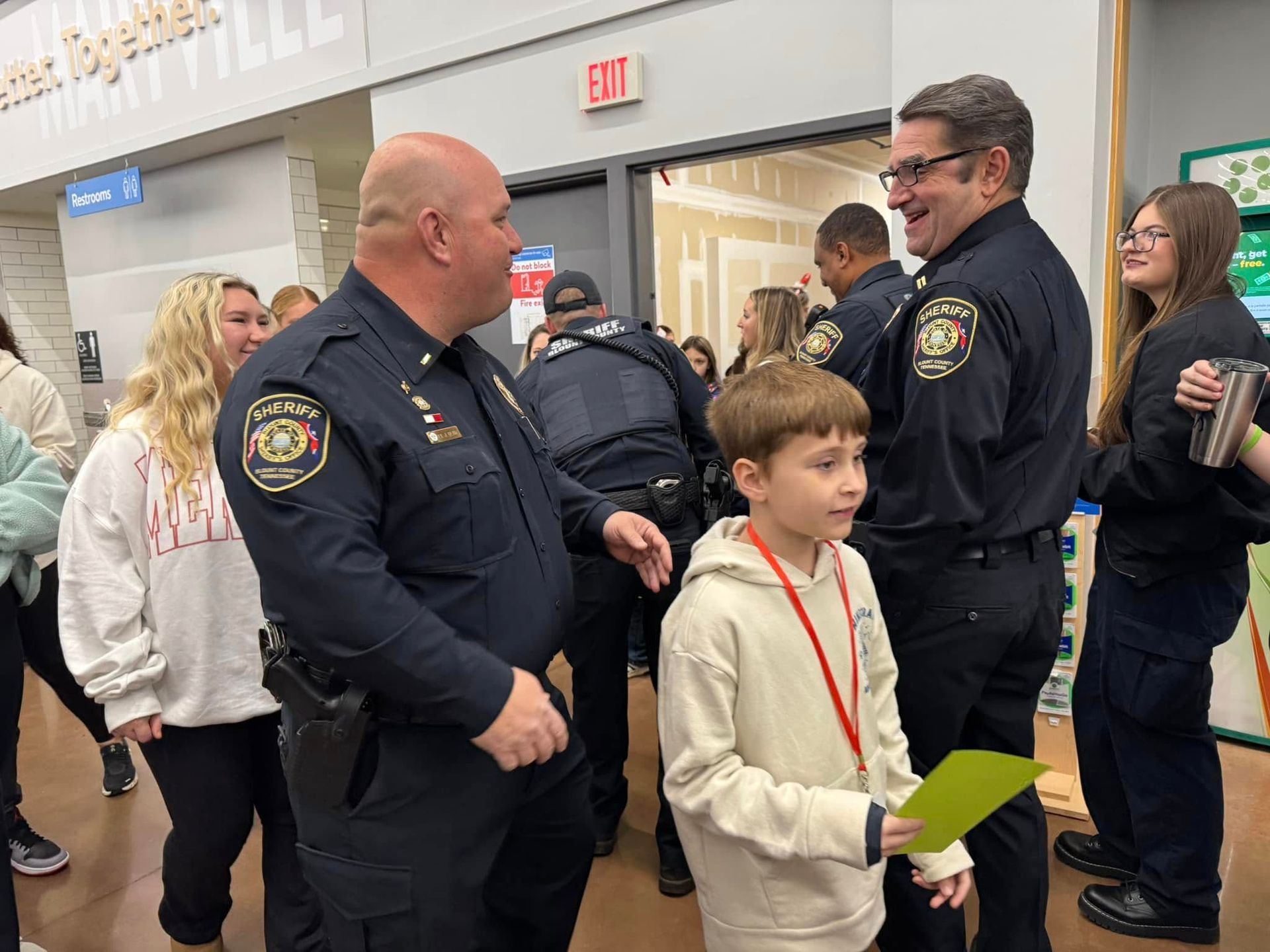 A group of police officers are standing next to each other in a store talking to a young boy.