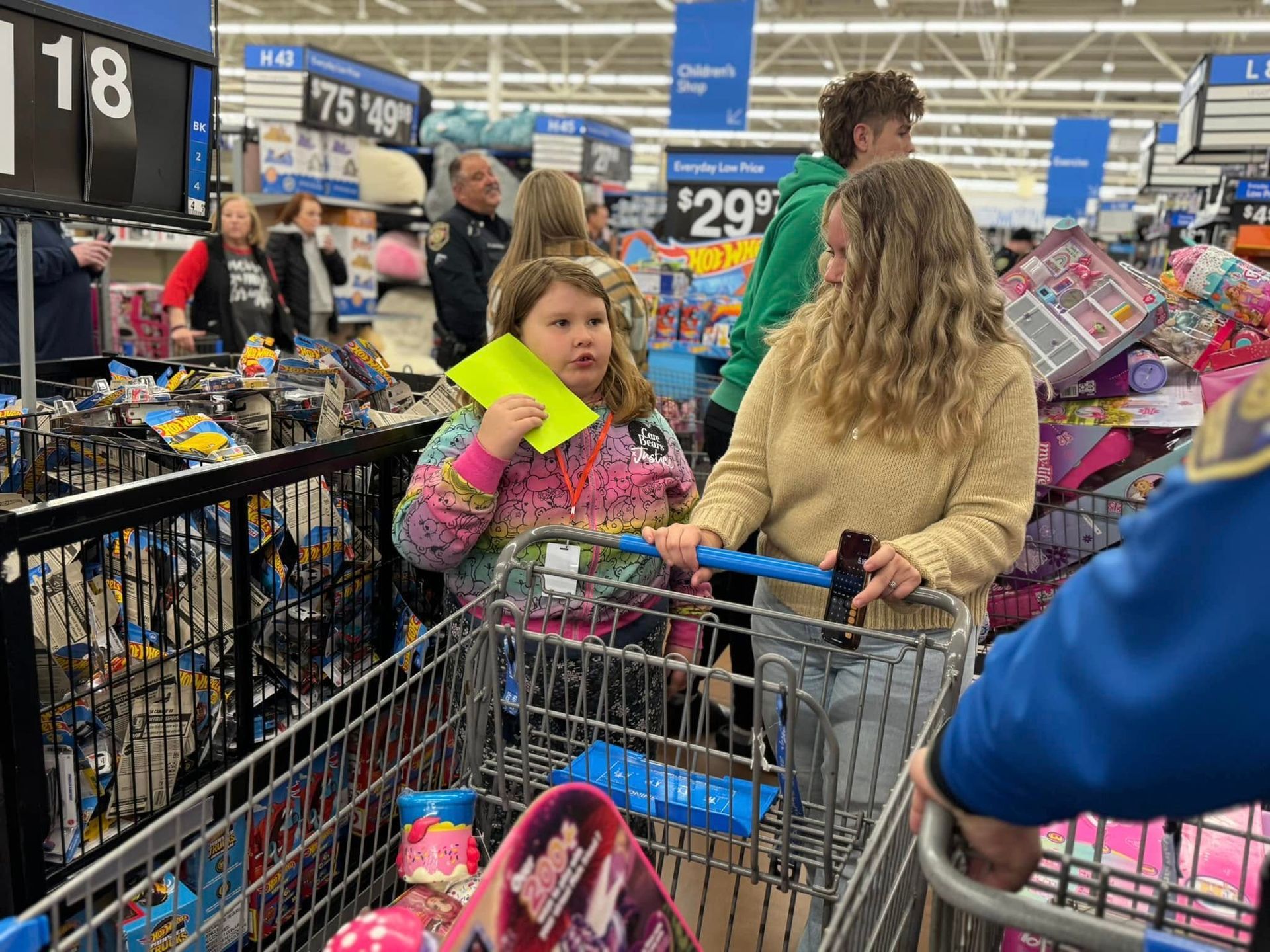 A woman pushing a shopping cart with a little girl in it in a store.