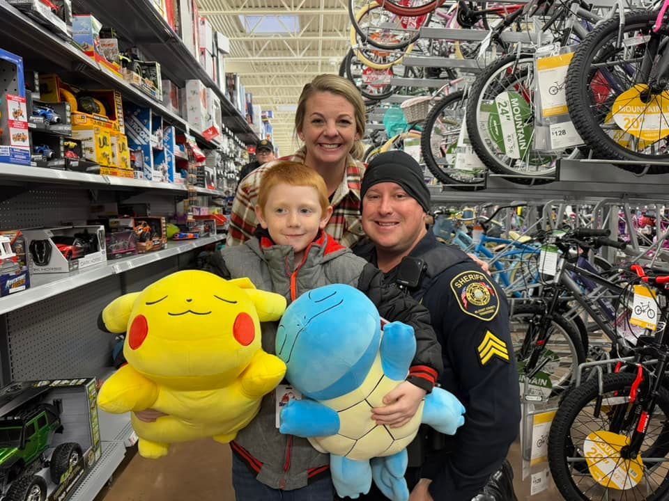 A family is posing for a picture in a store holding stuffed animals.