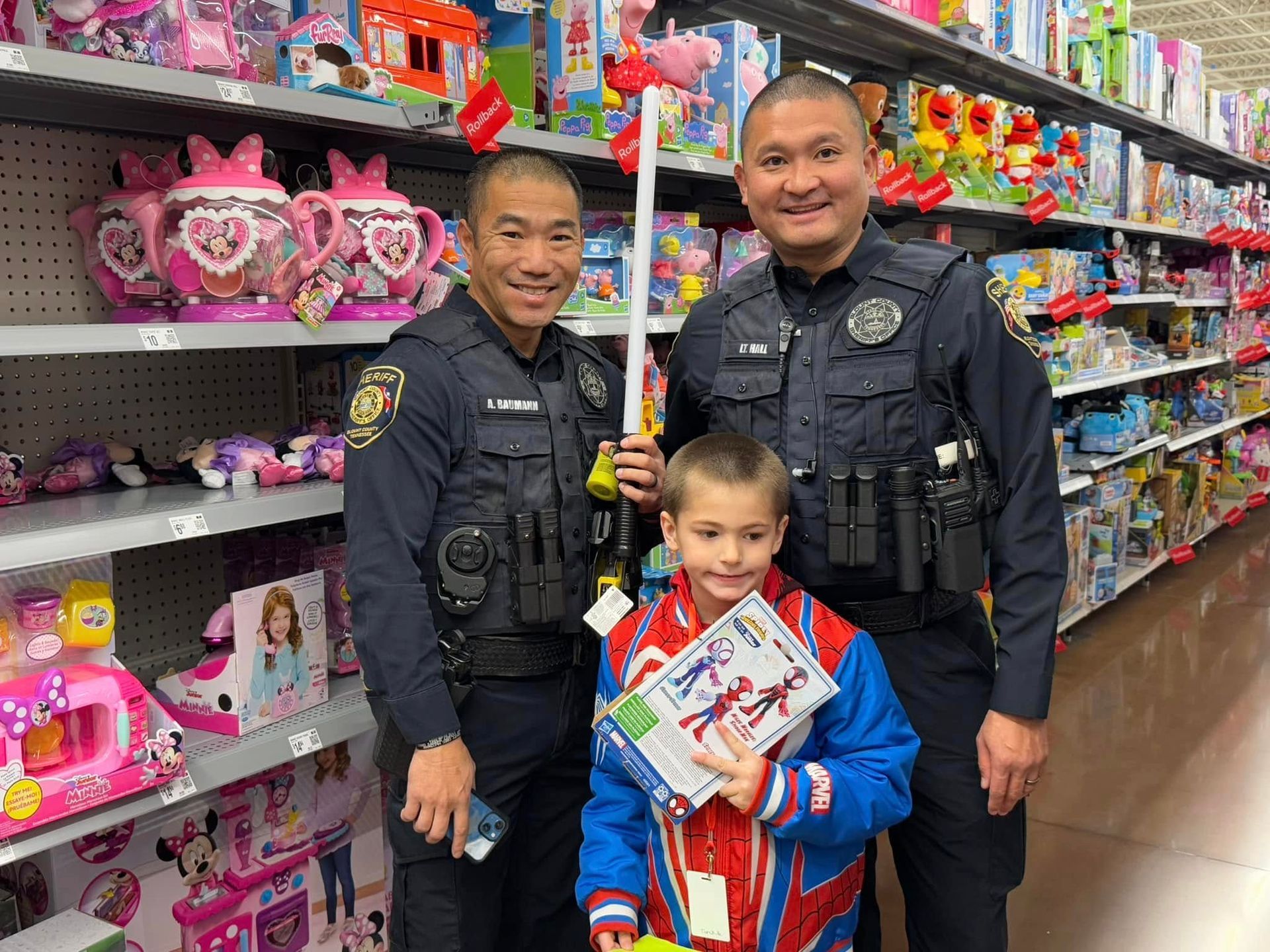 Two police officers and a boy are standing next to each other in a toy store.